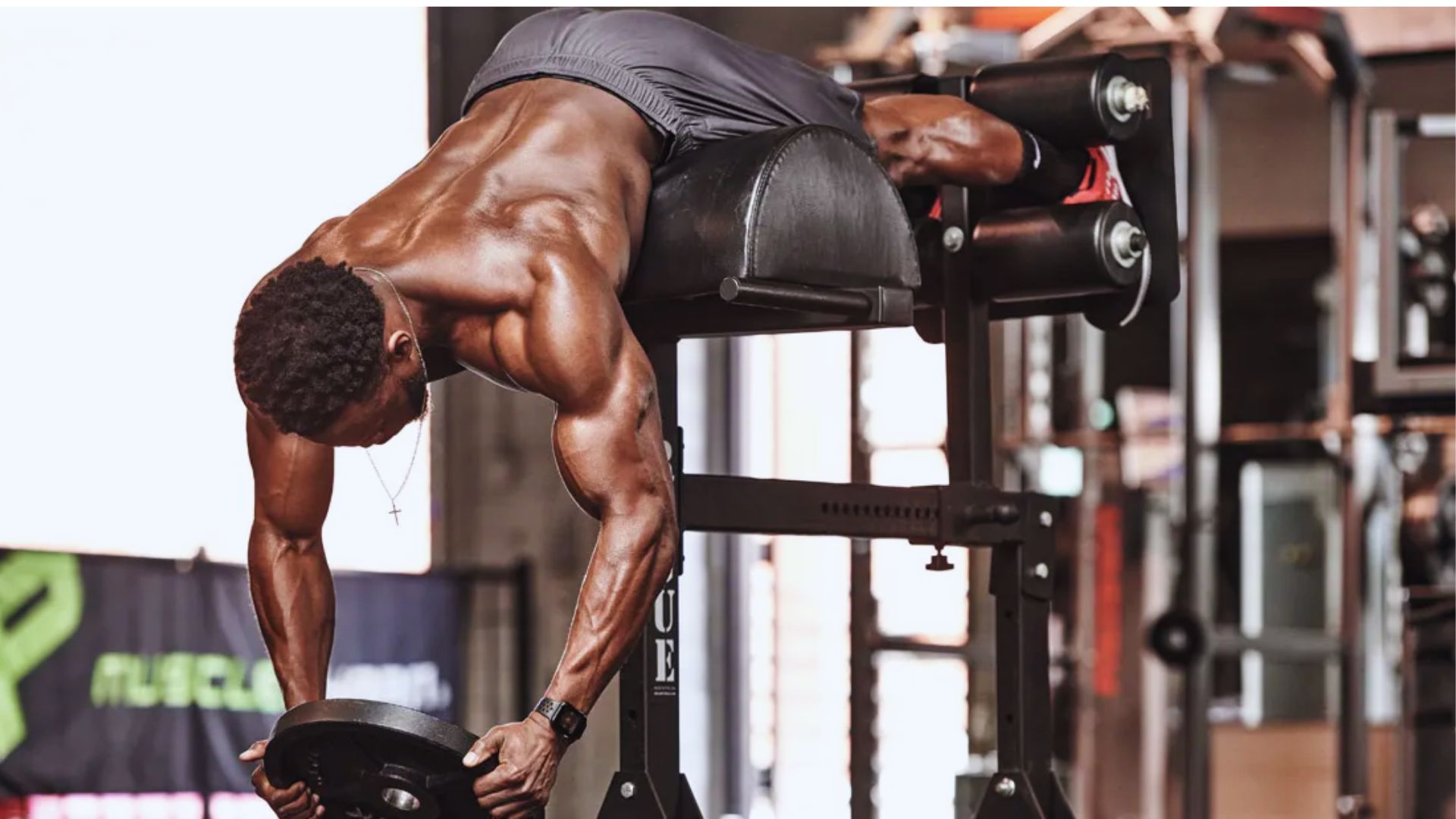 A man performing a push-up on a bench, demonstrating strength training in a weighted hyperextension exercise.