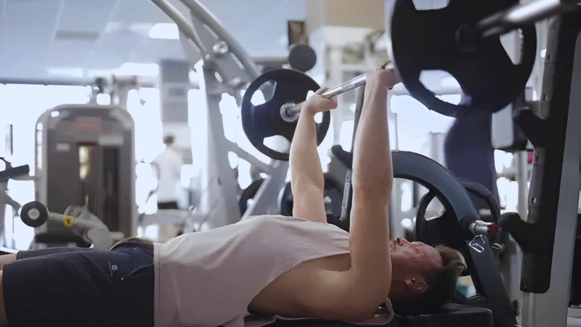 A woman performing a bench press in a gym, focusing on strength training and fitness.
