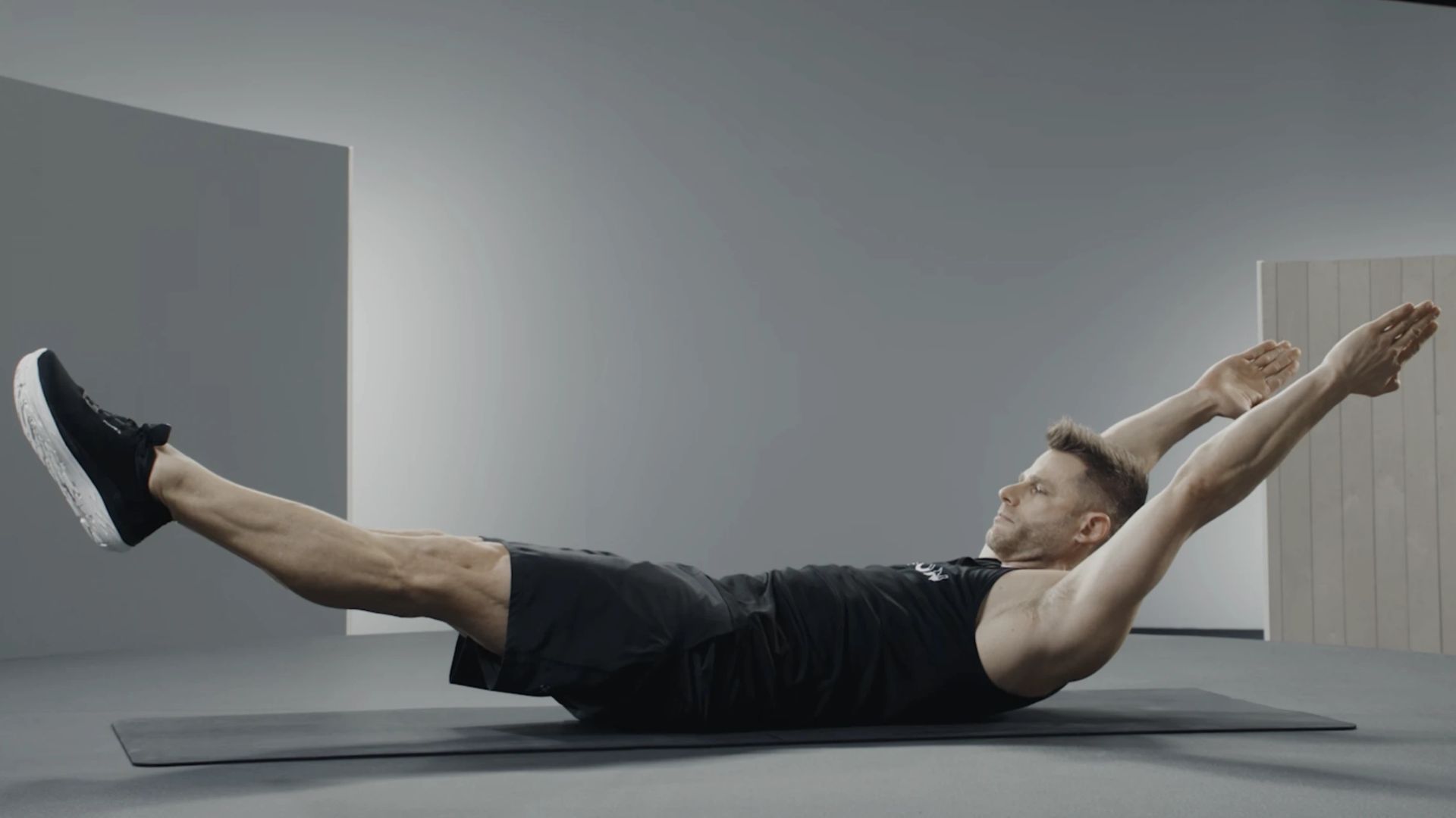 A man exercises on a mat, showcasing his physical activity in a spacious and bright setting.