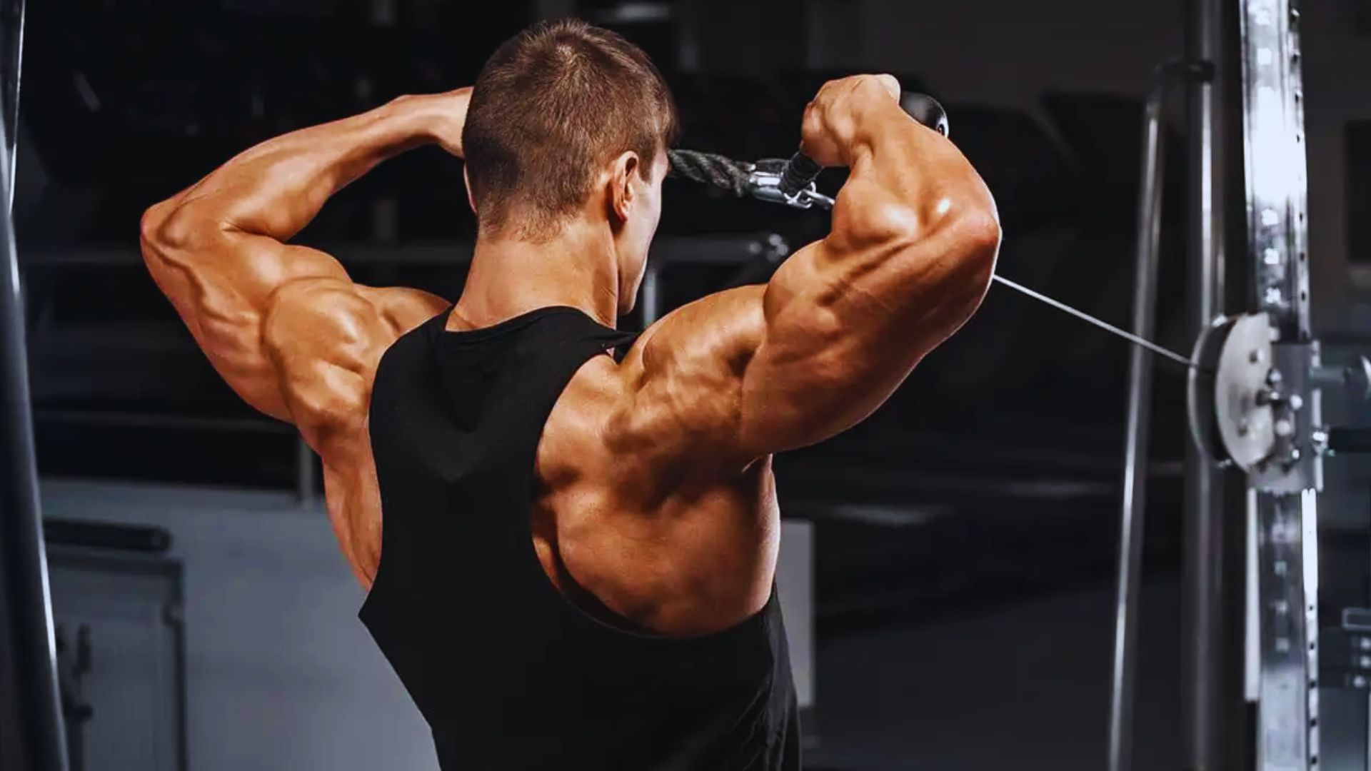 A man performs a pull-up in a gym, showcasing strength and focus on his workout routine.
