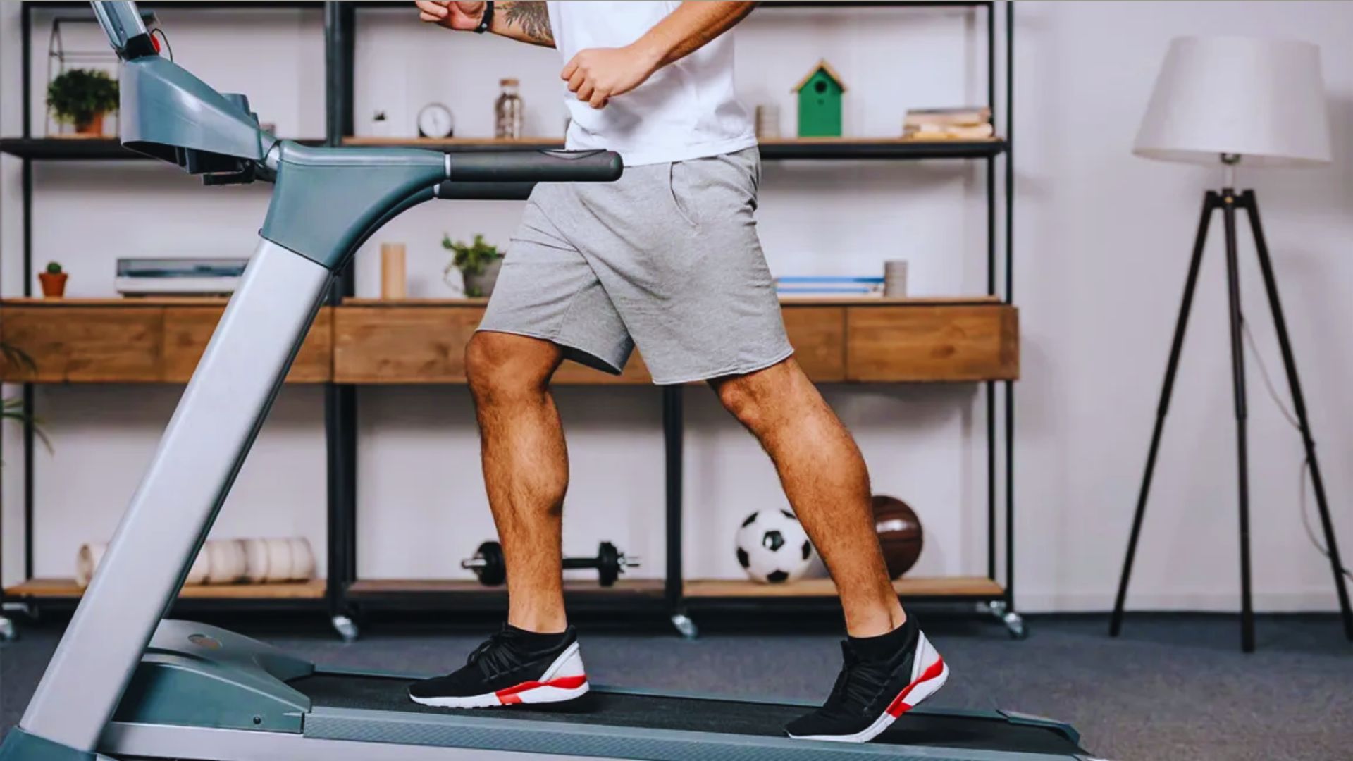 A man is jogging on a treadmill in a well-lit exercise room, focused on his workout.