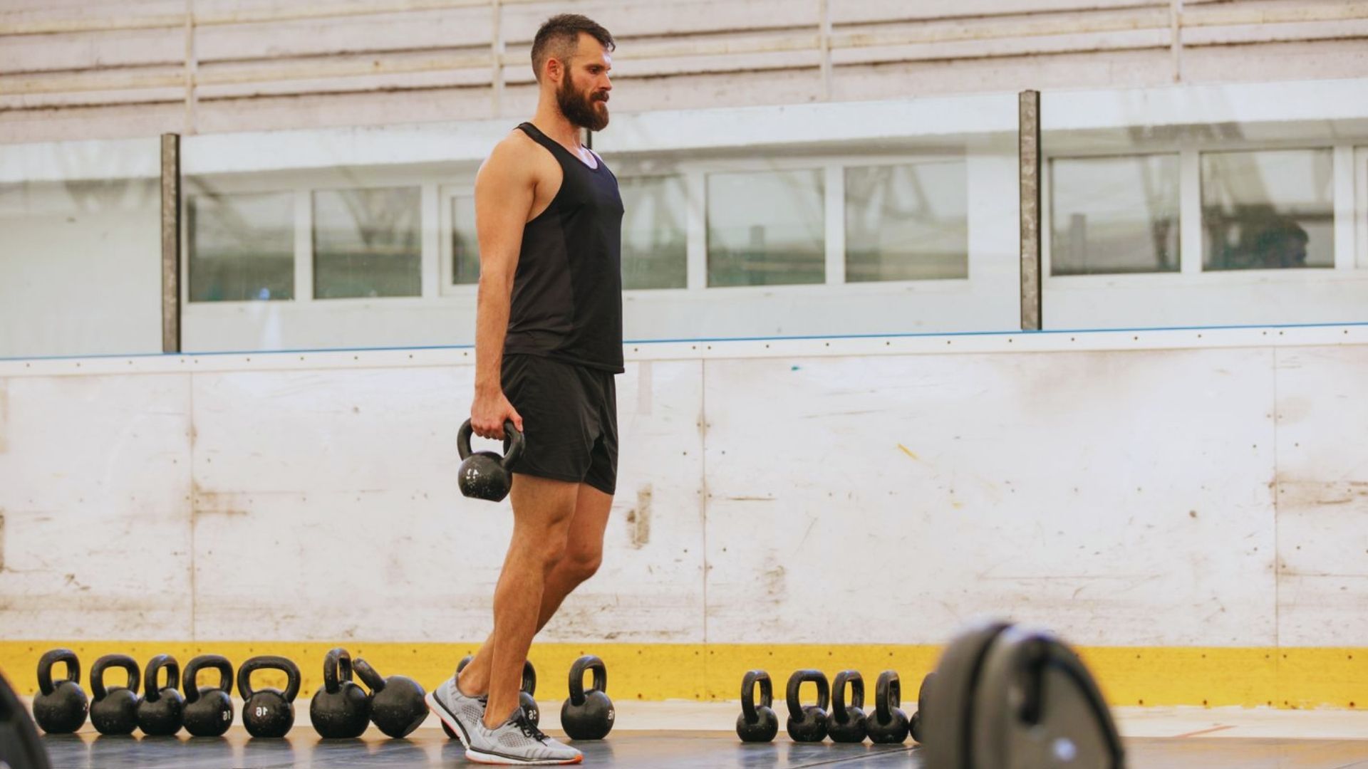 A man stands confidently in front of a kettlebell, ready for a workout session.