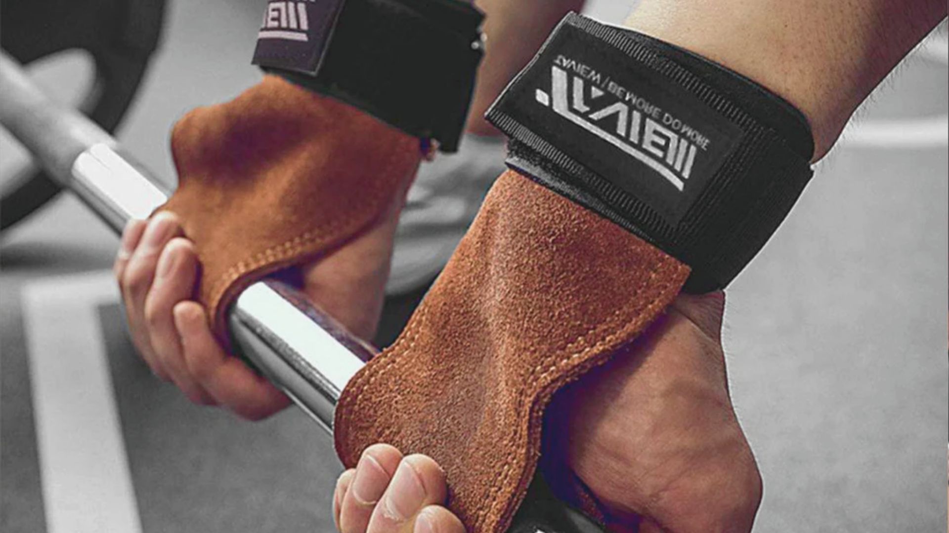 1. A person gripping a bar secured with a wrist strap, demonstrating proper handling technique for weightlifting.