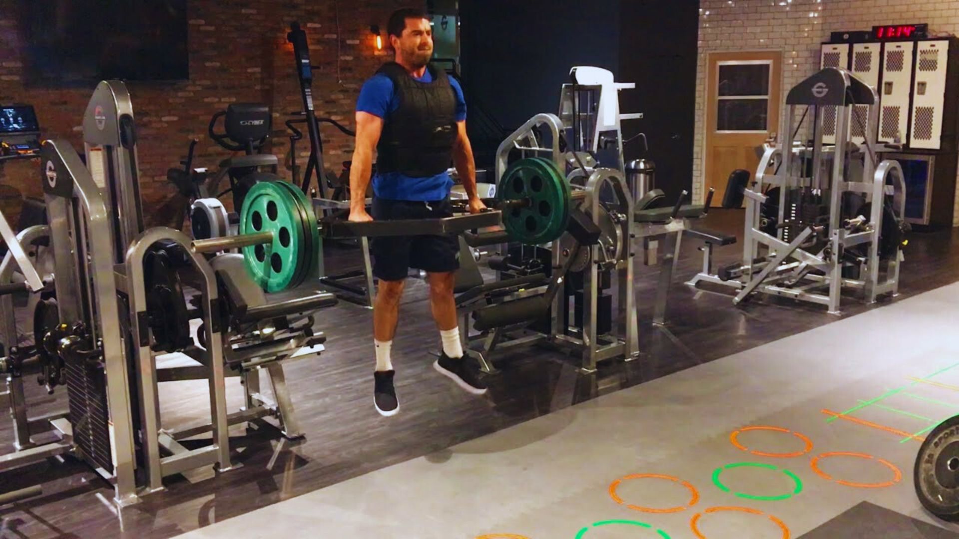 A man is engaged in a squat exercise at the gym, demonstrating proper technique and concentration.