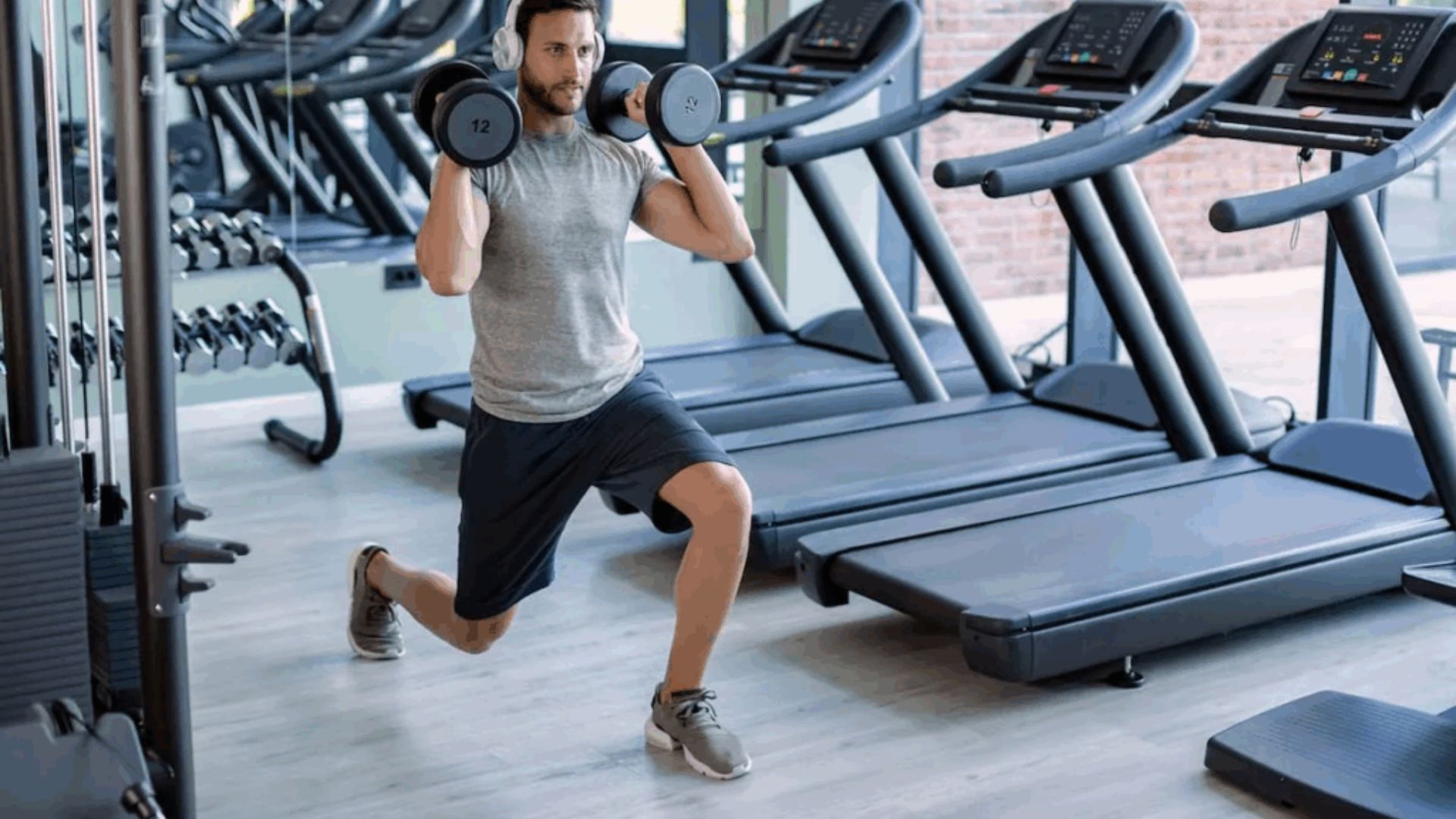 A man performs a cardio workout with weights in a gym, focusing on strength and endurance training.