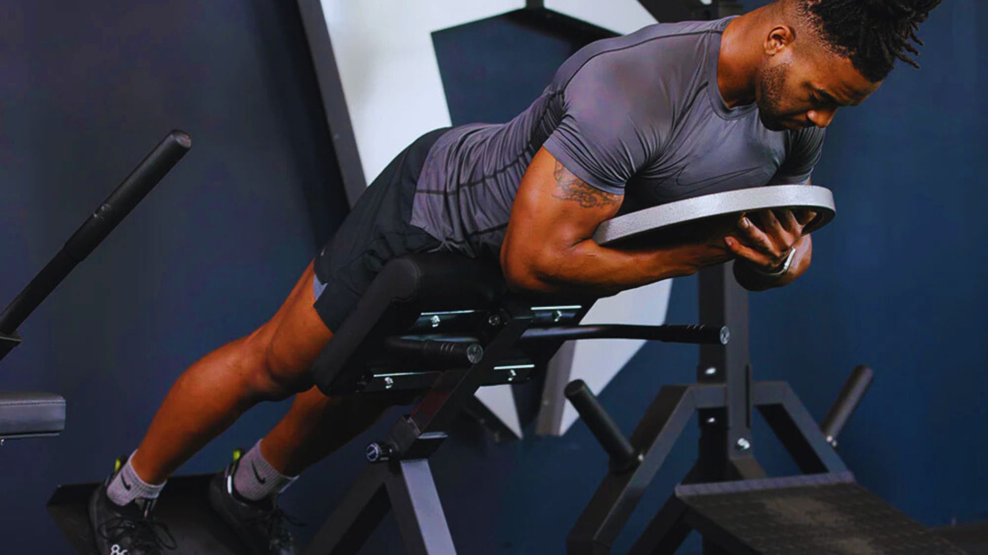 A man performs abs on a Roman chair hyperextension bench, focusing on core strength training and fitness.