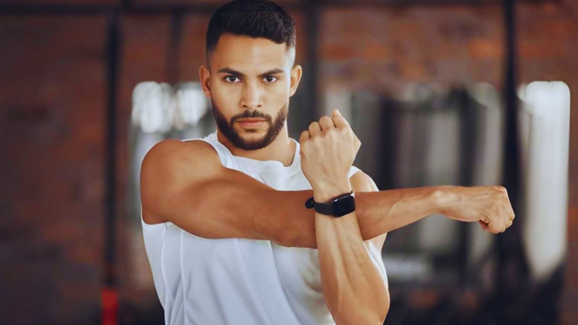 A man flexes his arm, displaying his biceps and wearing a watch, highlighting techniques for bicep and forearm recovery.