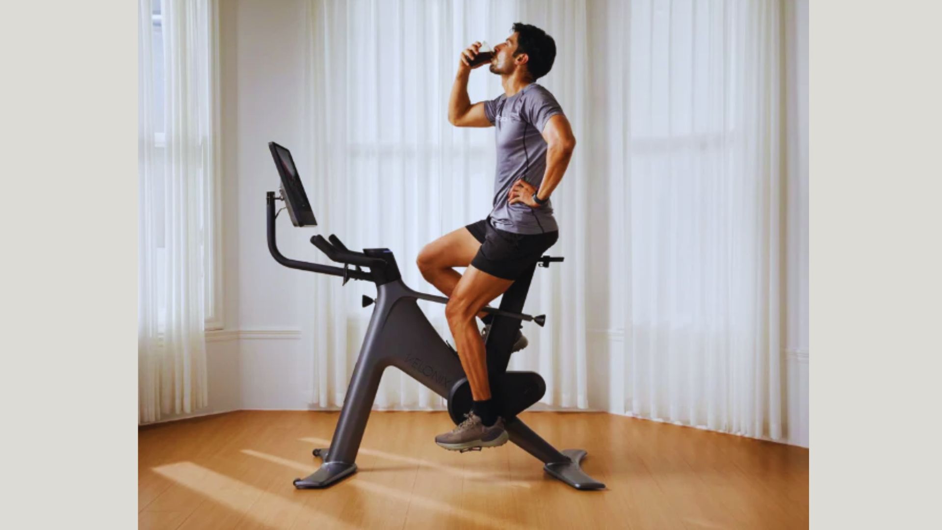 A man pedals on an exercise bike in a bright room, engaged in his workout session