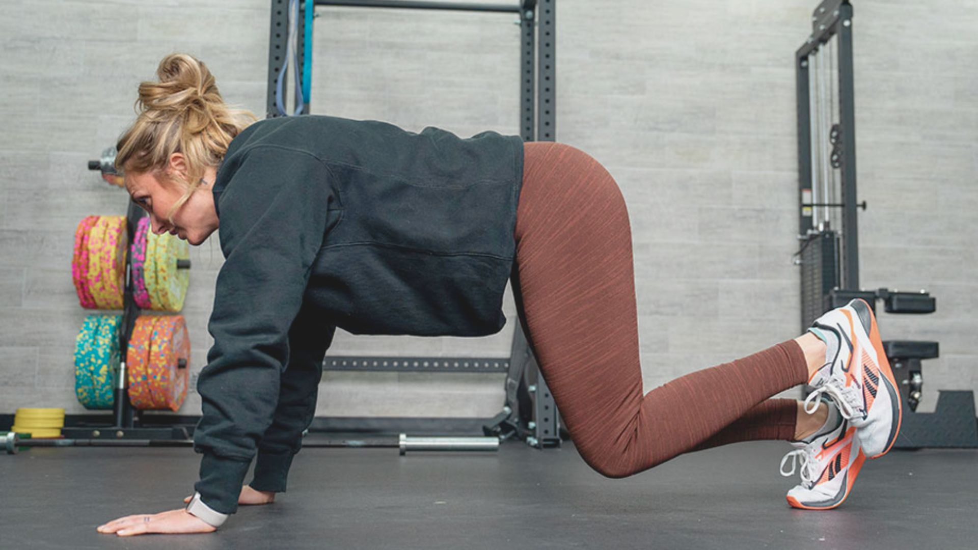 A woman performing push-ups on a gym mat, focusing on her fitness routine in a well-equipped gym environment.