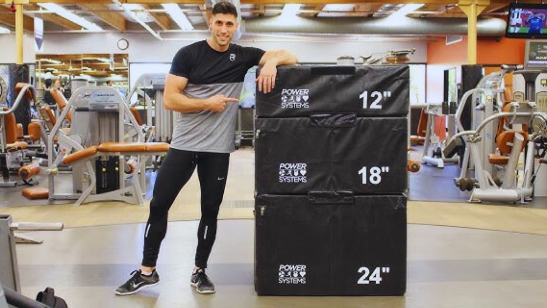 In a gym, a man is positioned next to a large box, possibly for exercise or fitness training.