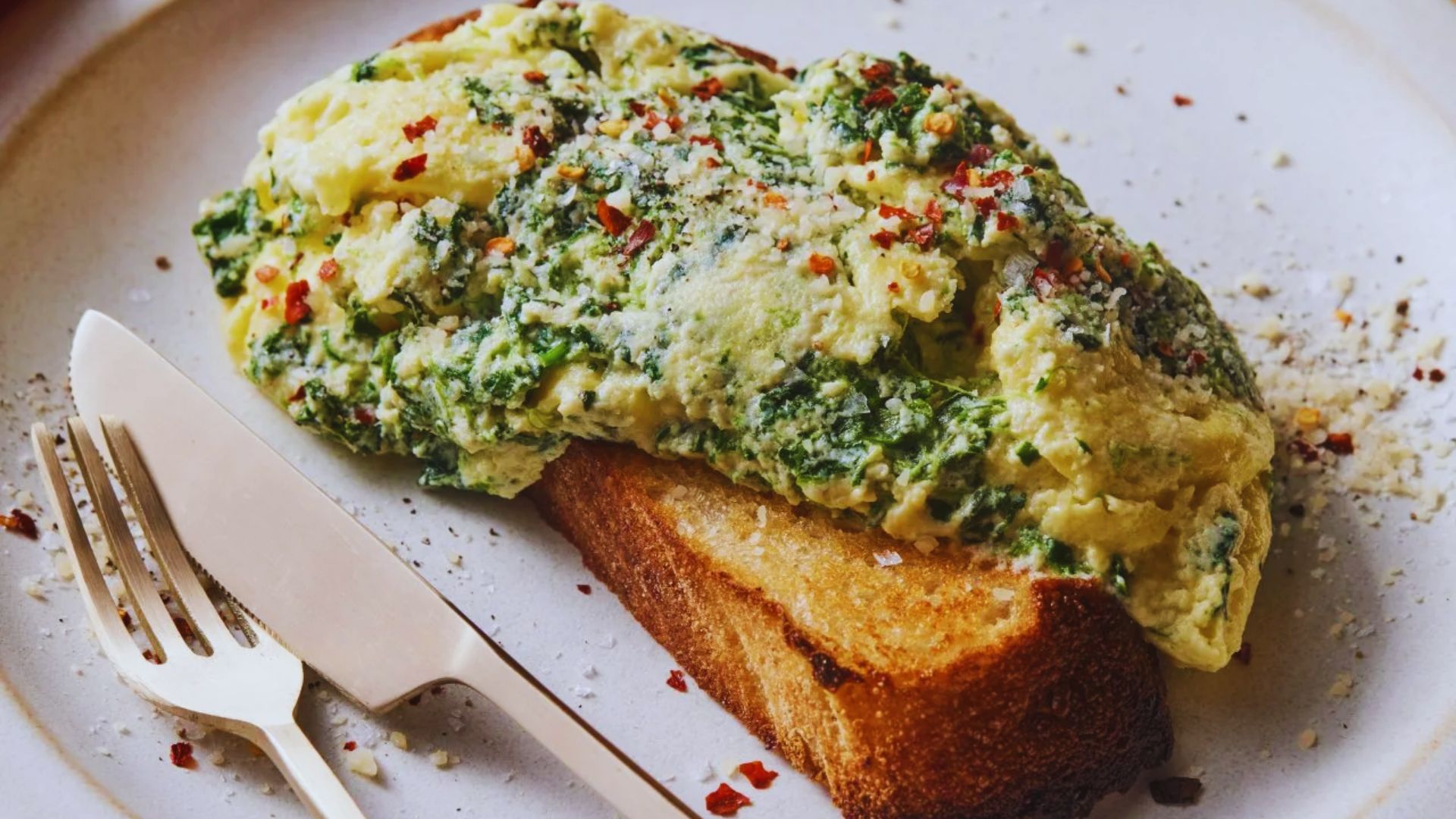 A plate of toast topped with sautéed spinach and poached eggs, garnished with a sprinkle of black pepper.