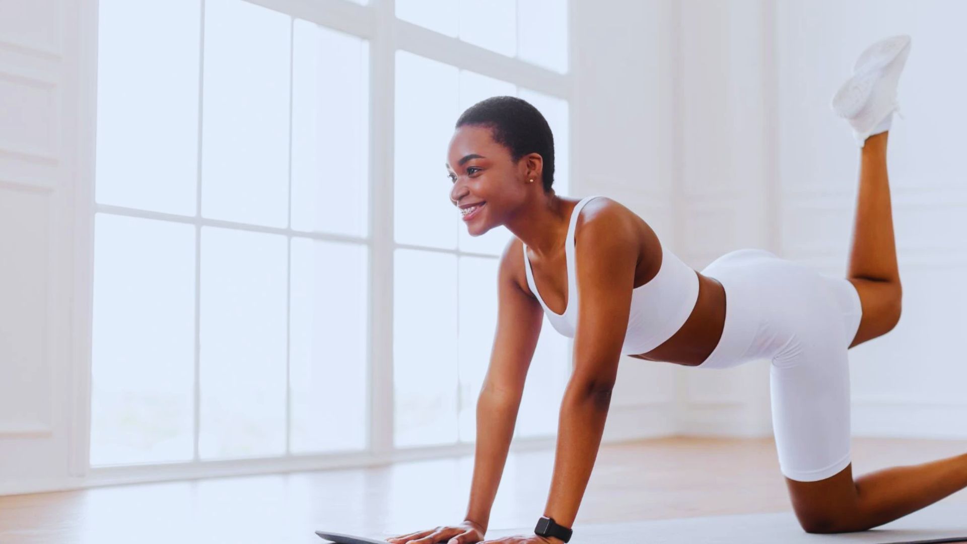A woman dressed in white sportswear executing a yoga pose, showcasing balance and focus in a tranquil setting.