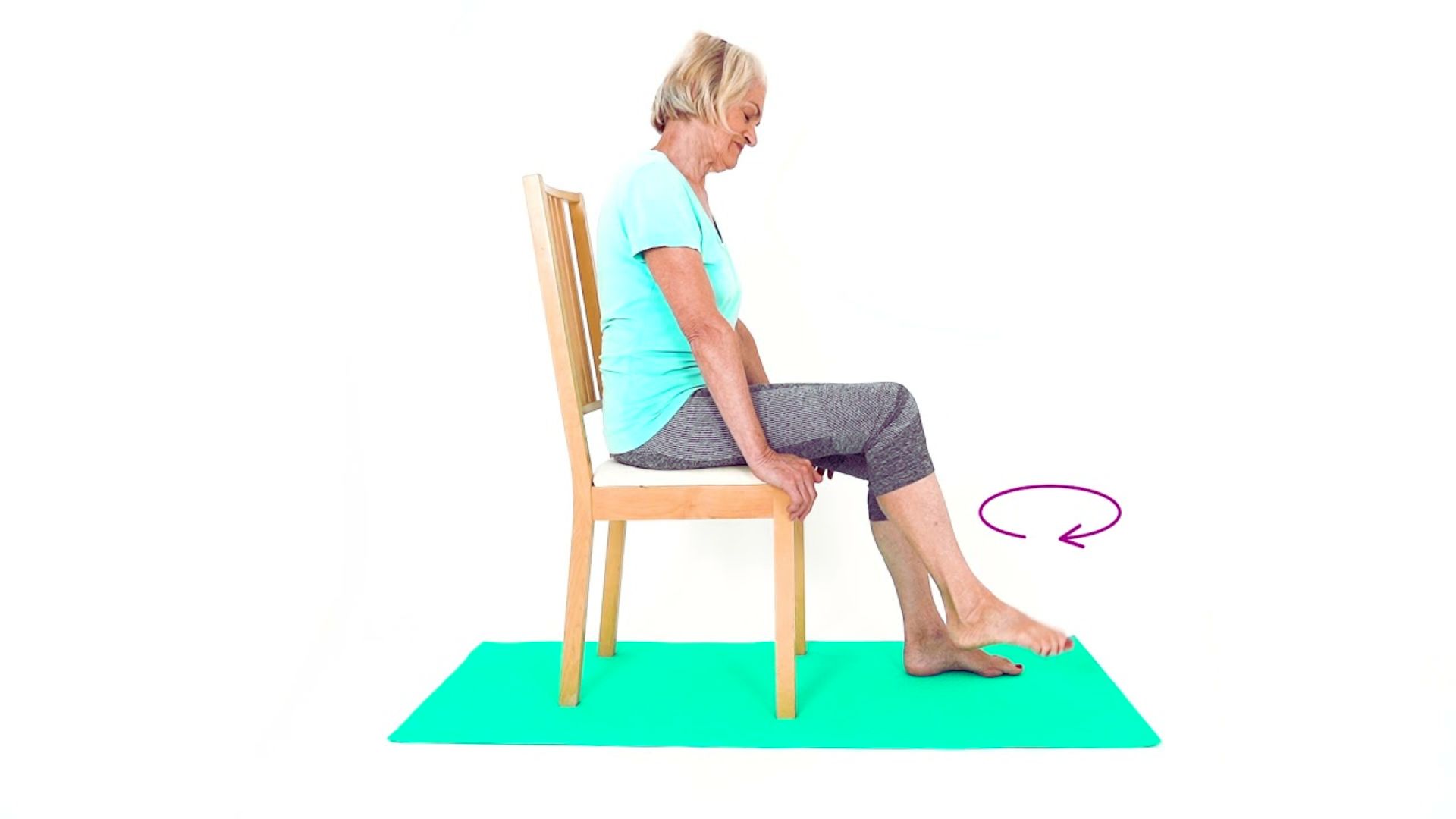A woman seated on a chair, resting her foot on the floor, appears relaxed and engaged in her surroundings.