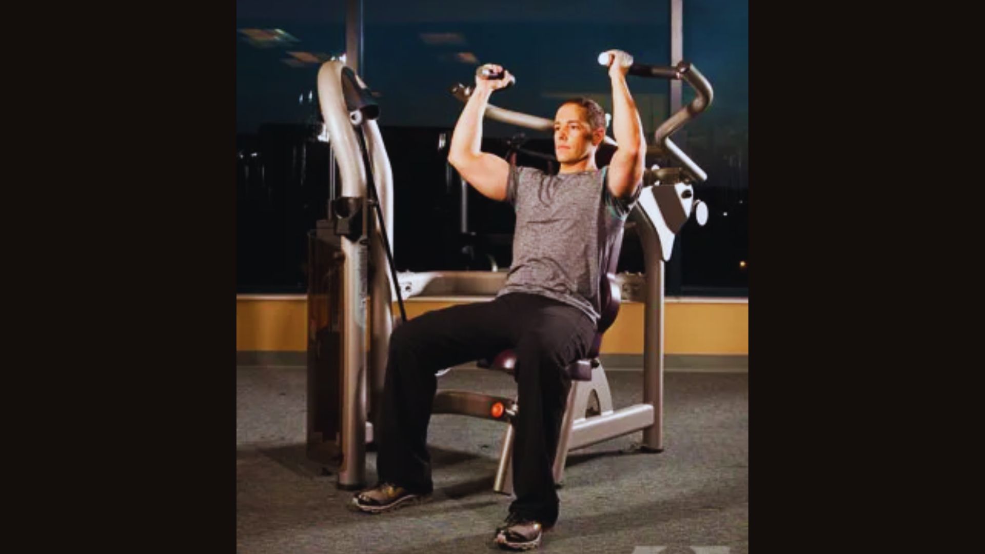A man performs a pull-up on a machine, focusing on proper grip and form for effective shoulder press exercise.