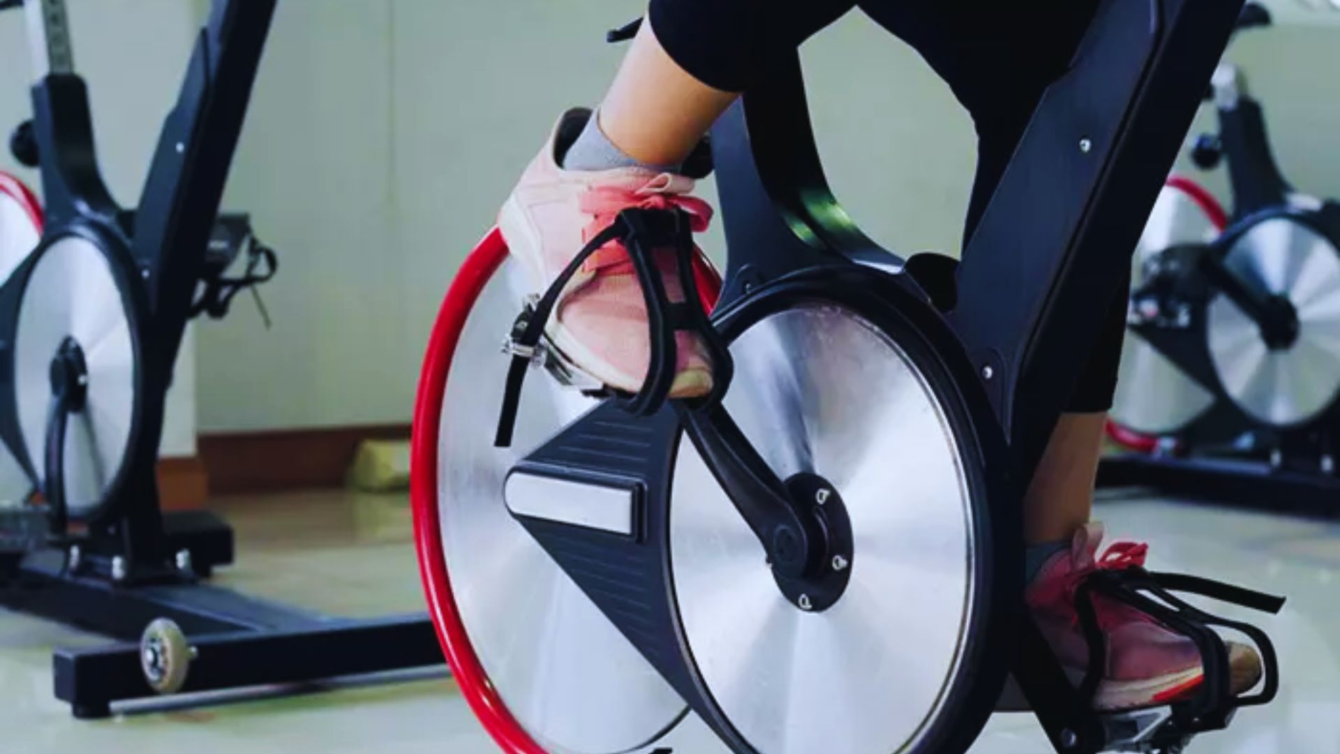 1. A person pedaling on an exercise bike in a gym, focused on their workout amidst various gym equipment.