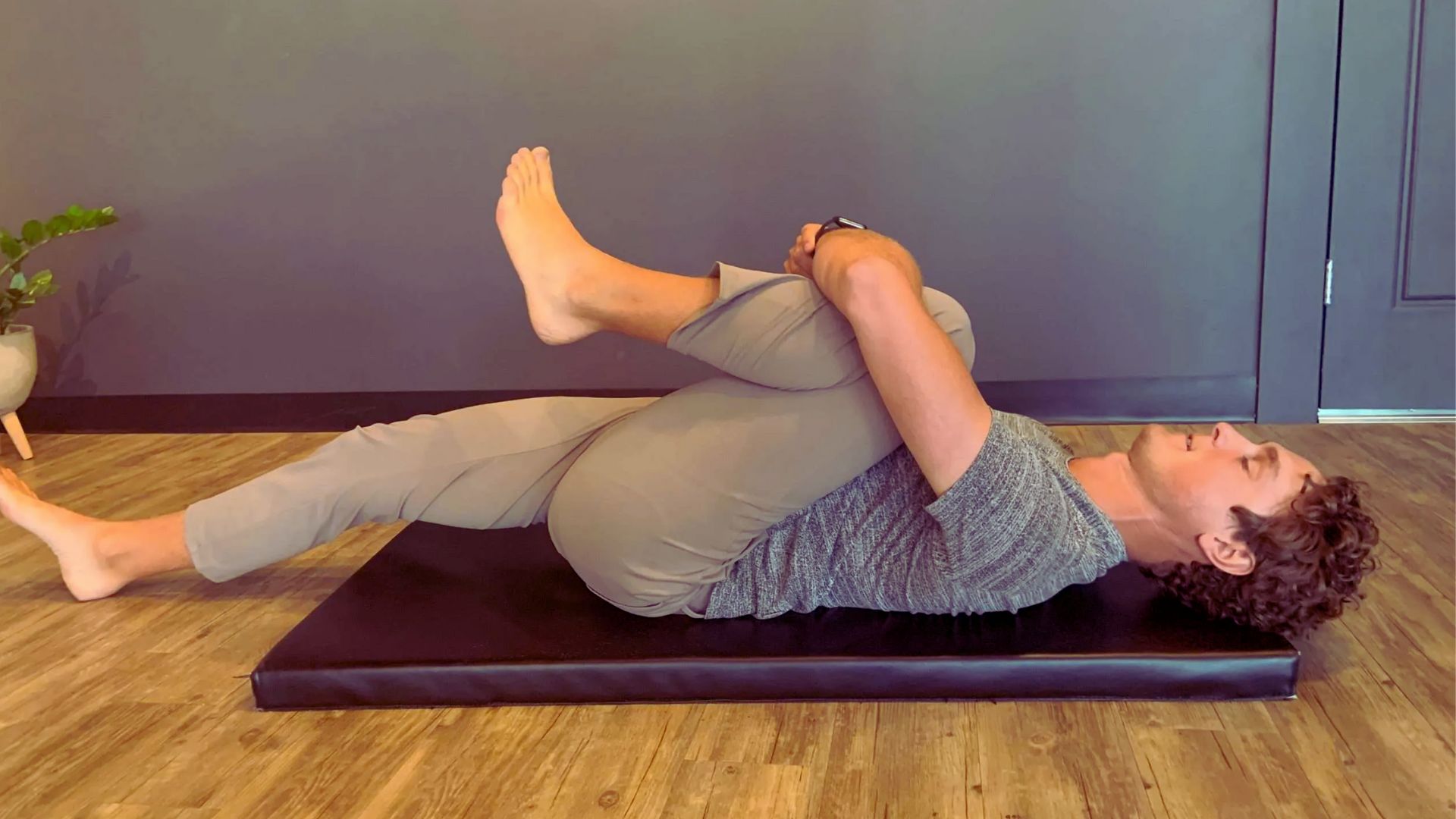 A man performs a yoga pose on a mat, demonstrating balance and focus in a serene environment.