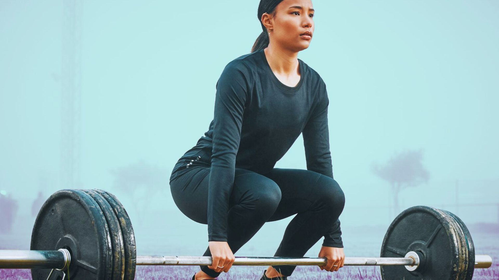 A woman performs a squat with a barbell, demonstrating strength and proper form in a gym setting.