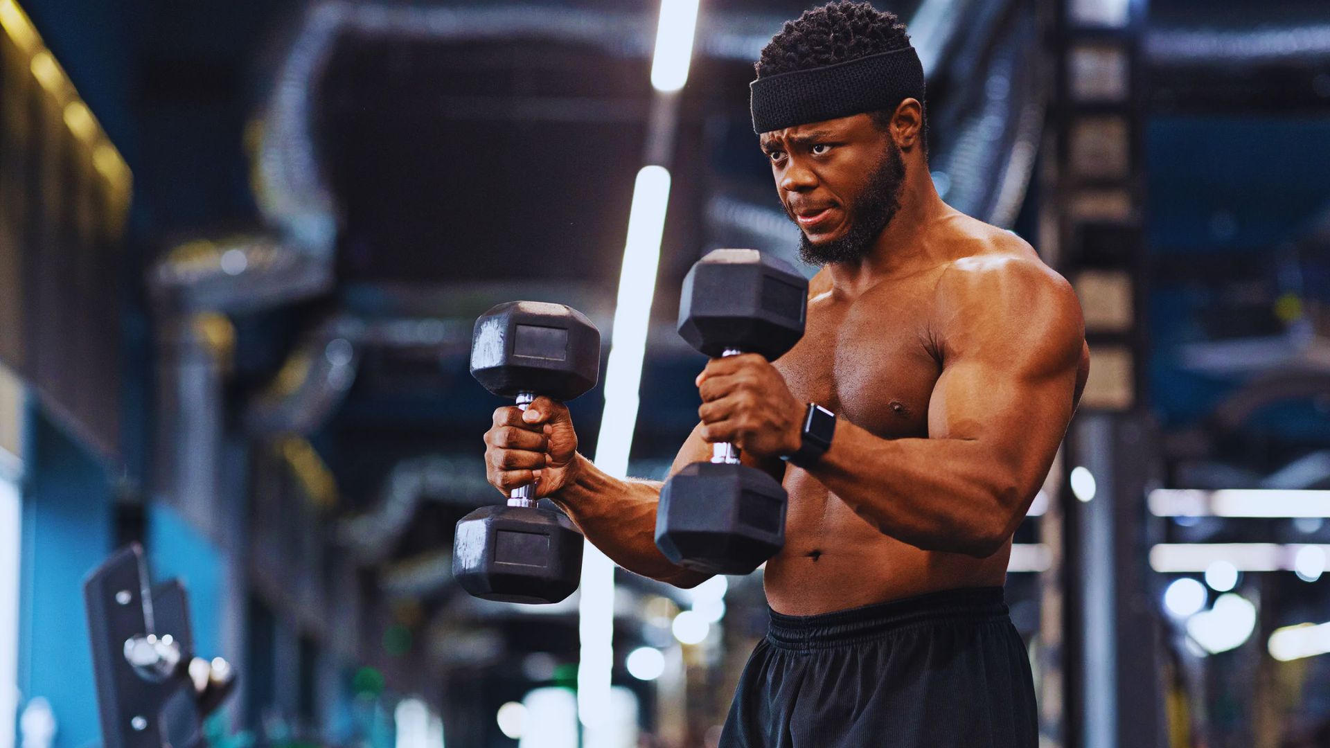 A man lifts weights in a gym, demonstrating hammer curls to strengthen his biceps and forearms.