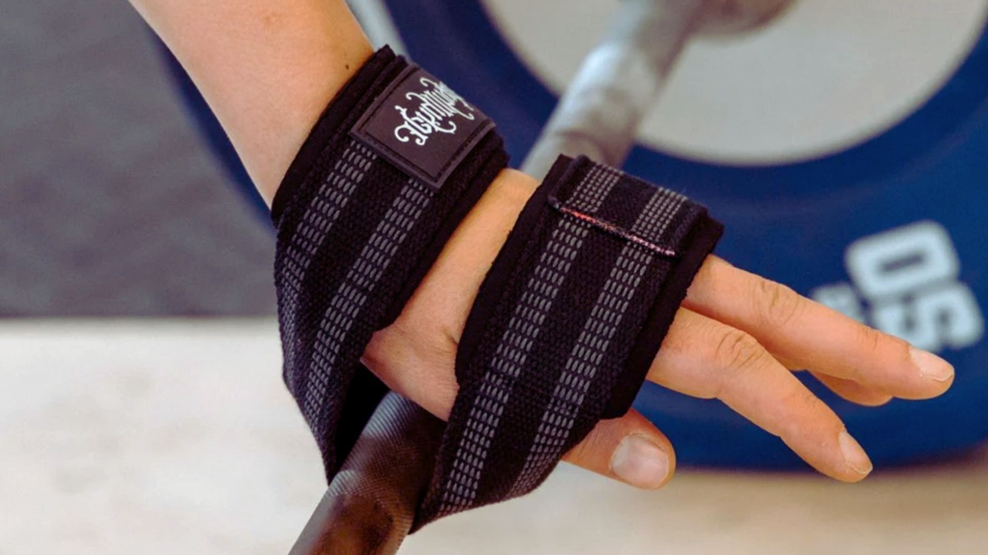 An individual holds a bar with a wrist strap, showcasing a secure grip for strength training exercises.