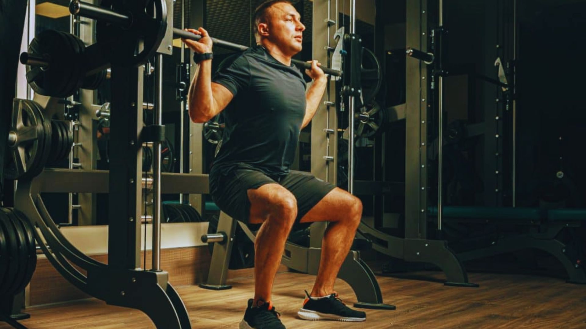 A man performs a squat in a gym, demonstrating strength and proper technique during his workout.