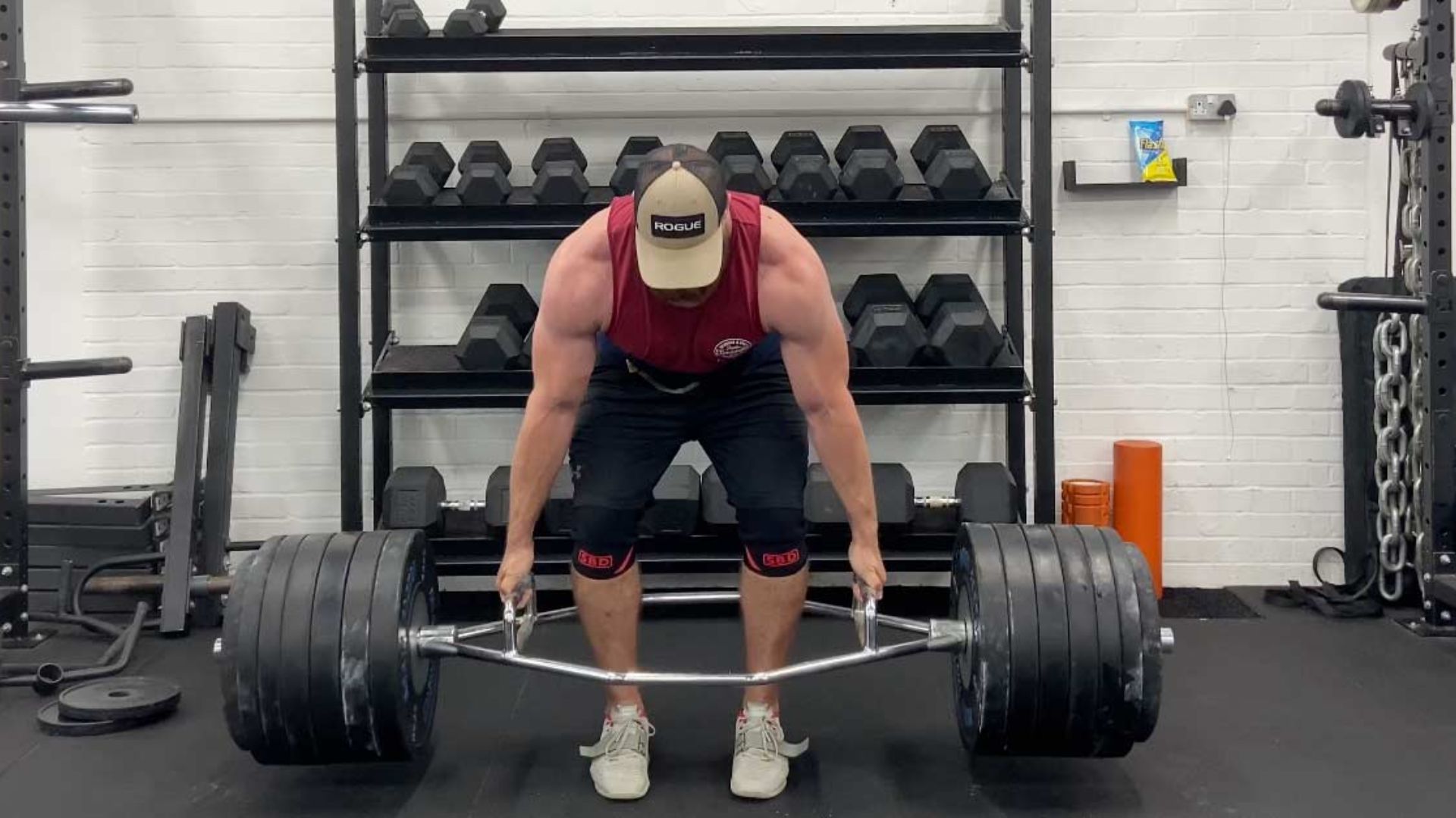 A person performing a trap bar deadlift, lifting a barbell on a platform with focused determination.