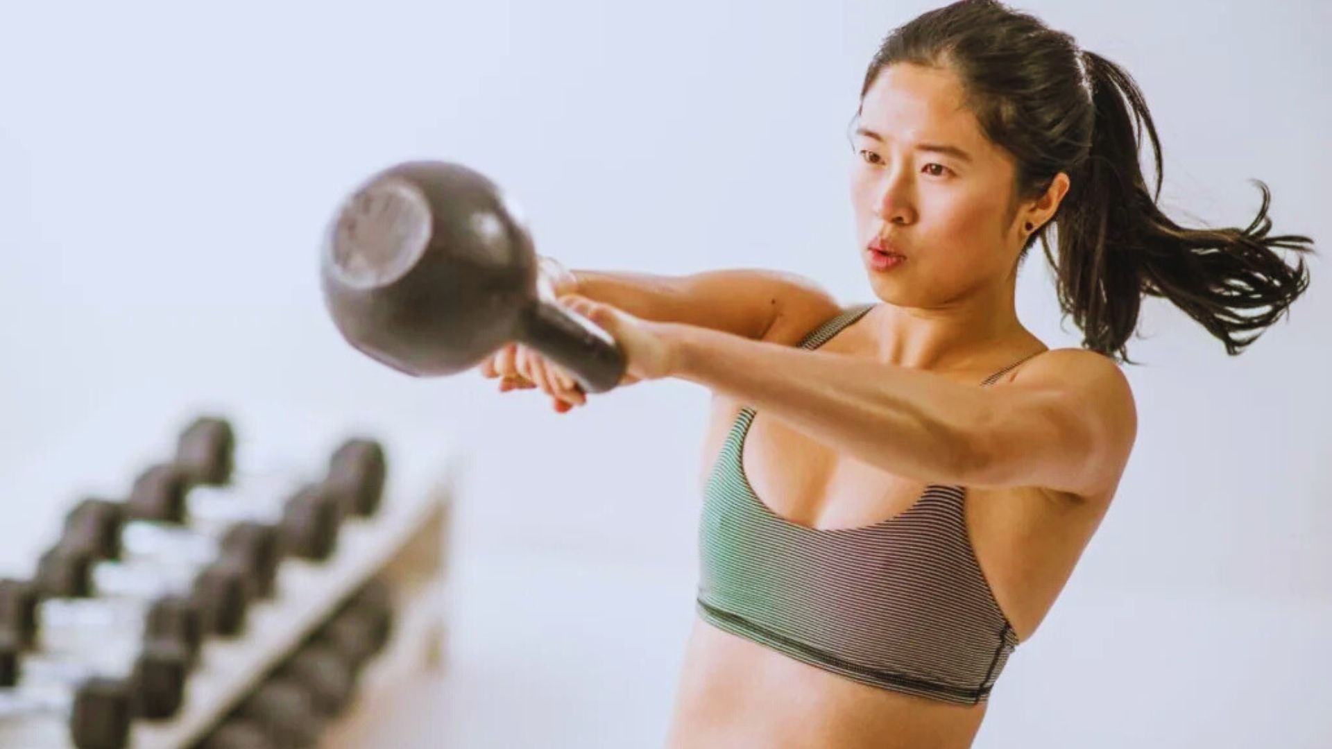 A woman grips a kettlebell, showcasing her commitment to fitness and strength training during an exercise session.