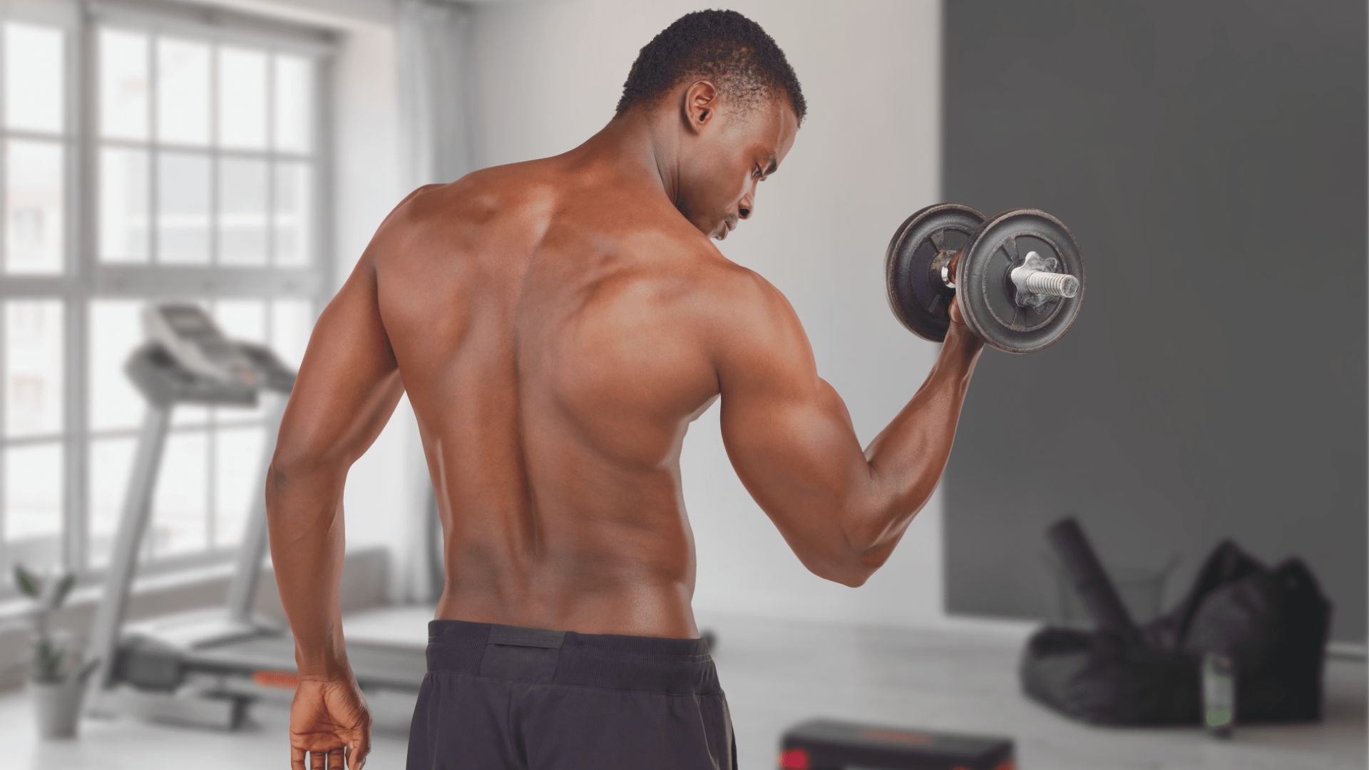A man lifts weights in a gym, focusing on his strength training routine amidst gym equipment.