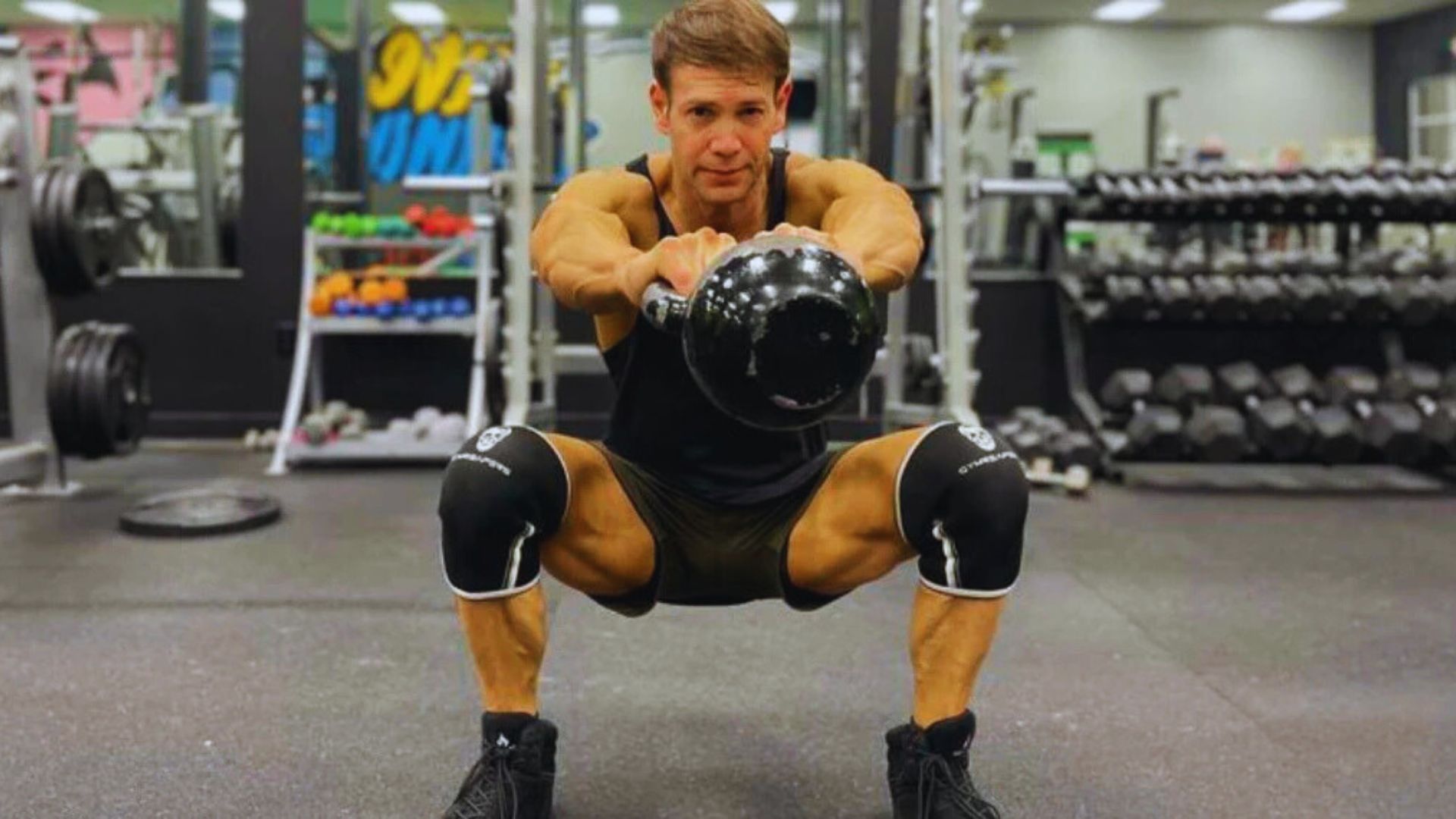 3. A man is seen squatting with a kettlebell in a gym, emphasizing his fitness regimen.