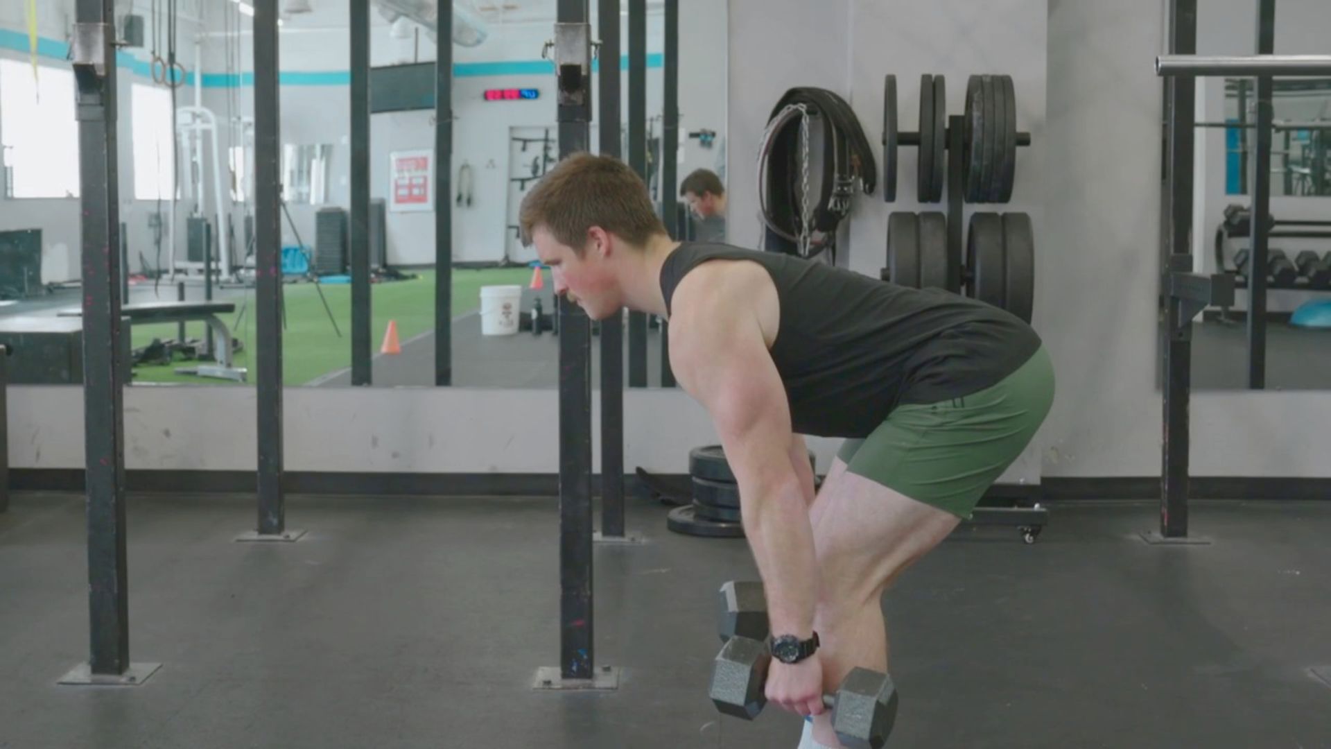 A man performing a squat in a gym, focusing on strength training with weights nearby.