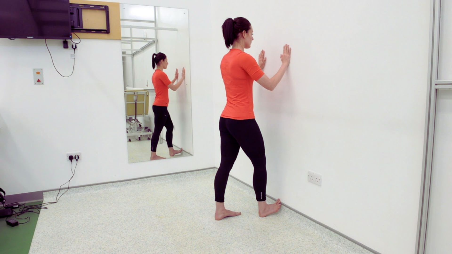 A woman stands in front of a mirror, examining her reflection with a thoughtful expression.
