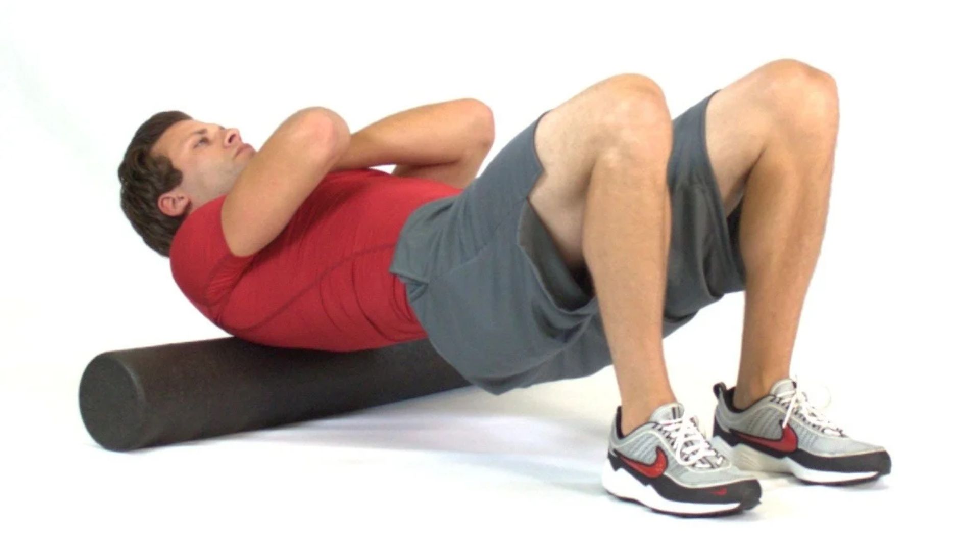 A man lies on a foam roller, performing an upper back release exercise for muscle relief and tension reduction.