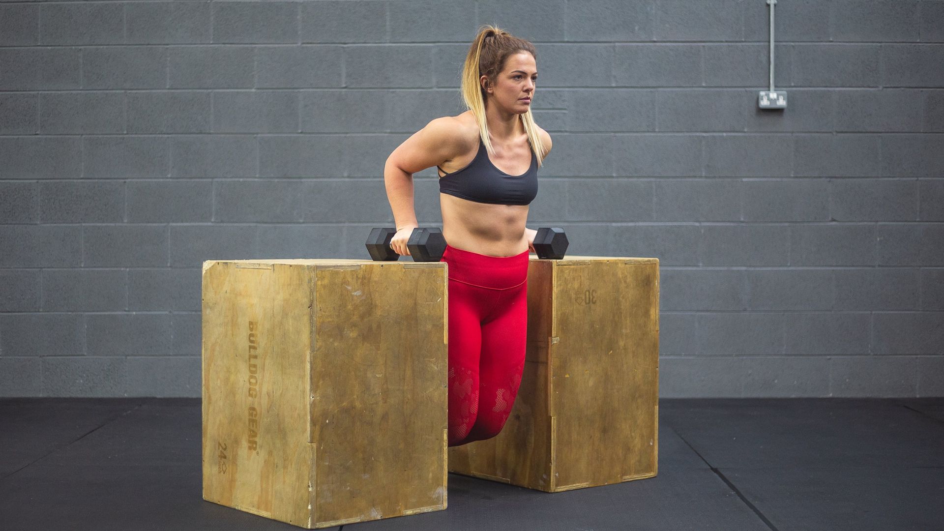 A woman performs a squat on a sturdy box, focusing on her form and balance during the exercise.
