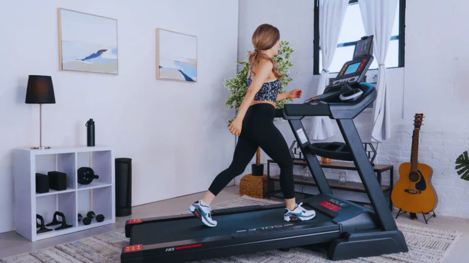 A woman runs on a treadmill in a well-lit room, focused on her workout.