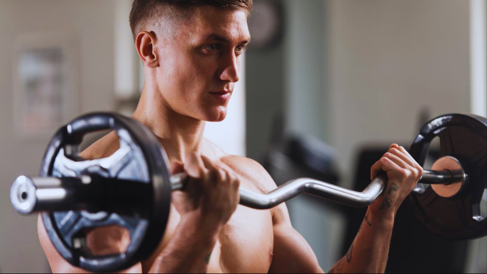 A man is lifting a barbell while exercising in a gym setting.