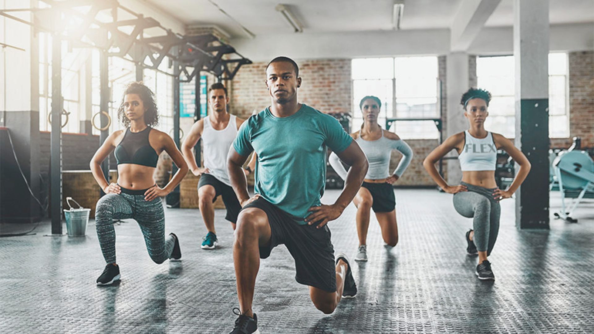 A group of individuals performing squats together in a gym setting, focusing on fitness and teamwork.