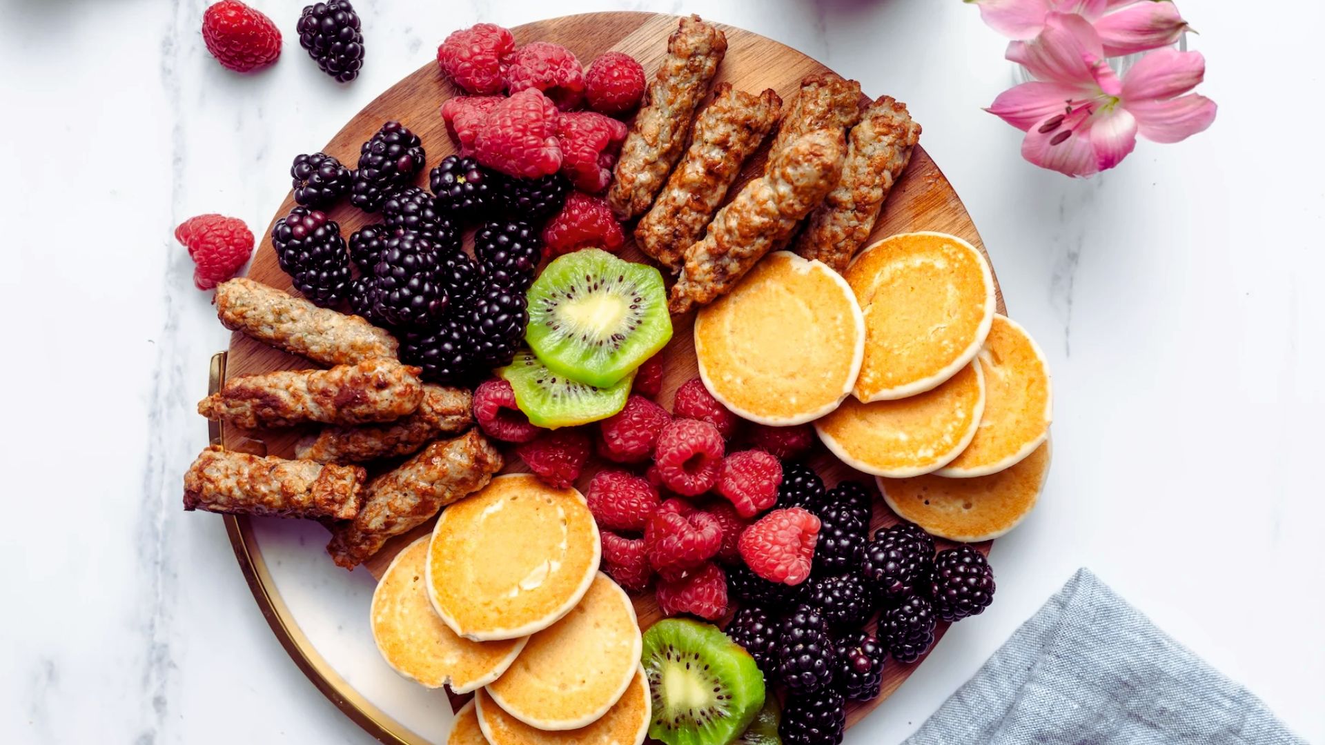A plate filled with fresh fruit and savory sausage links.