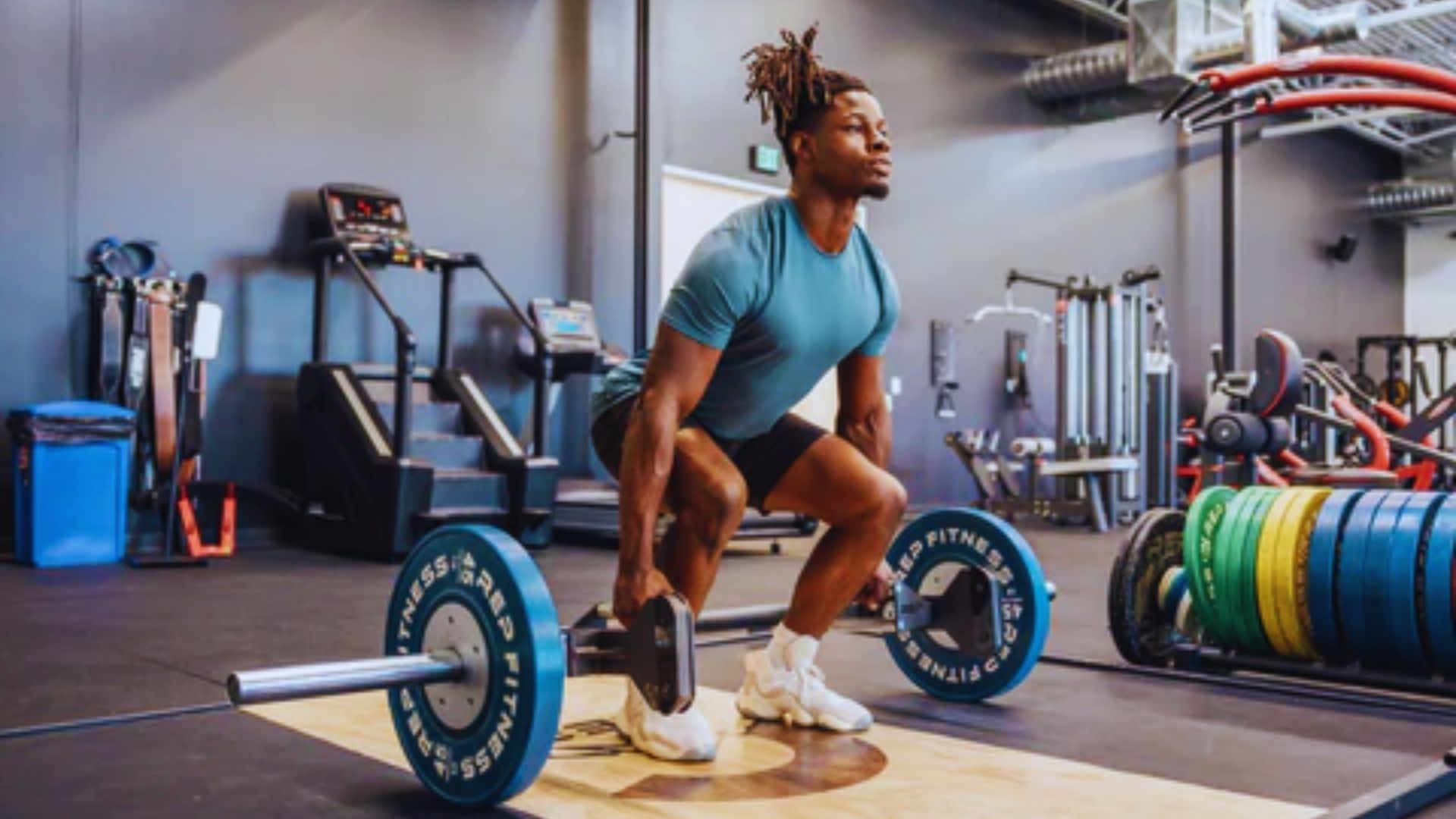 A man squats with a barbell on his shoulders in a gym, focusing on his form and strength training.