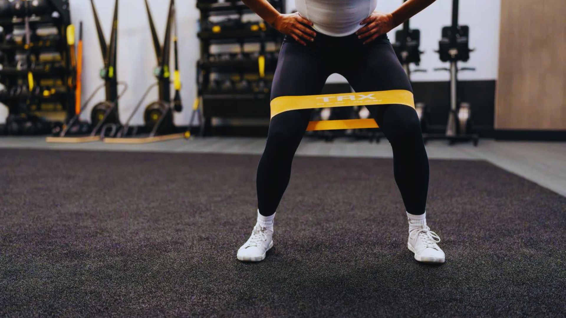 2. A woman is engaged in a squat exercise at the gym, demonstrating proper technique and fitness dedication.