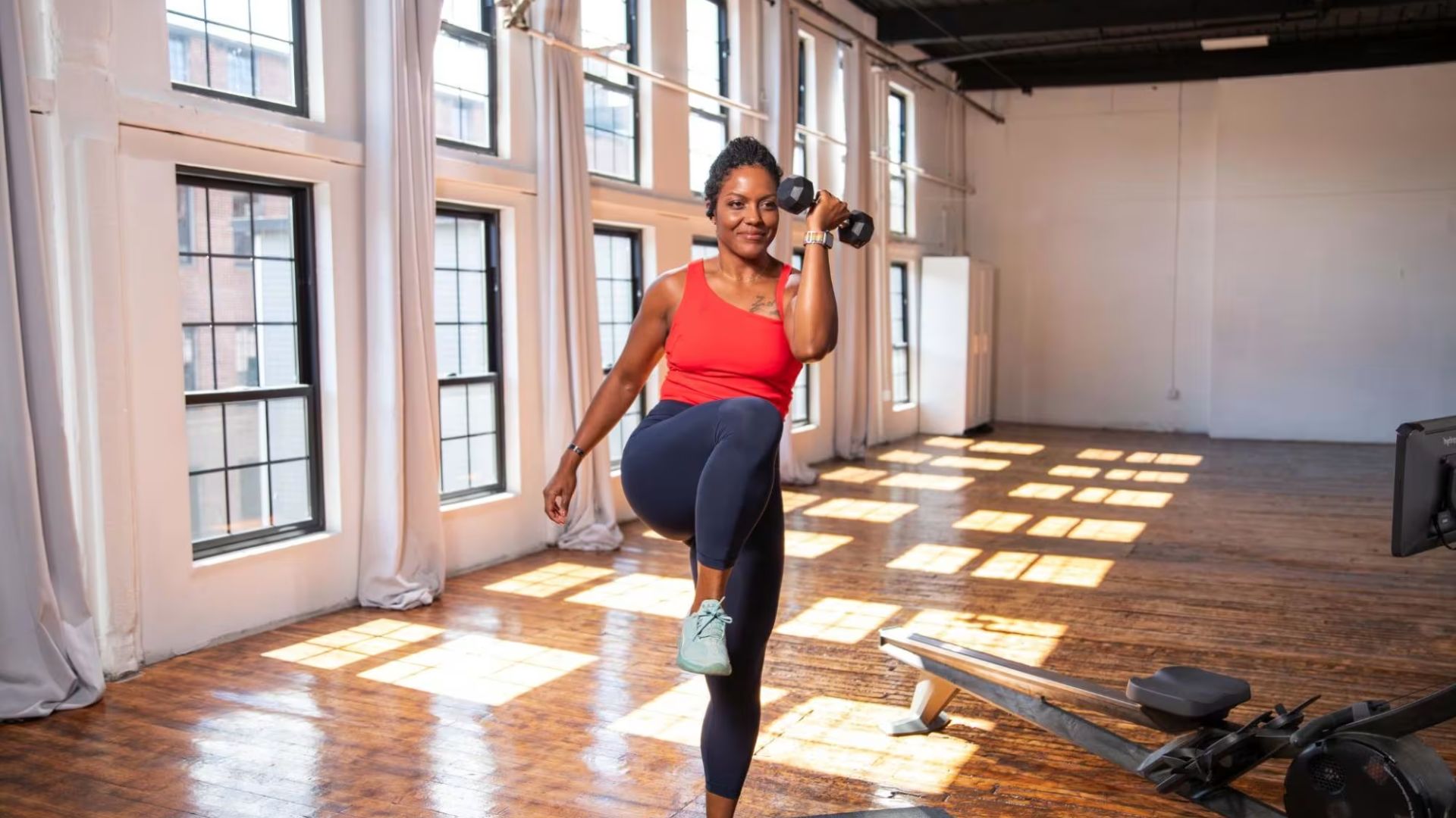 A woman performs a workout in a gym, focusing on her fitness routine with various equipment around her.