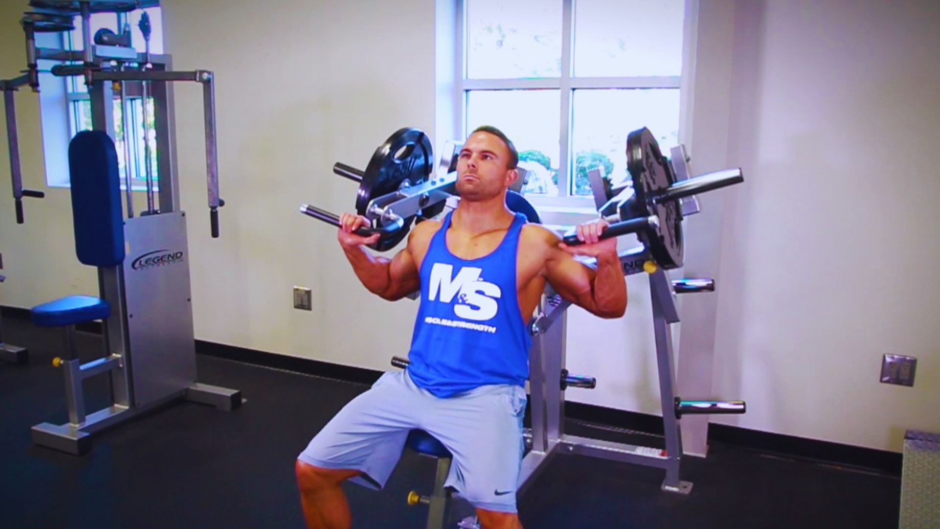 A man engaged in a bench press exercise using a shoulder press machine at Planet Gym