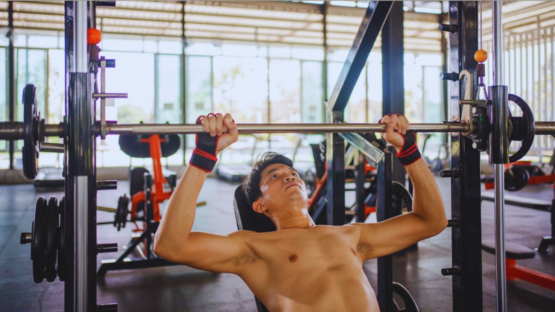 A man performs a pull-up on a bar in a gym, showcasing strength and fitness.