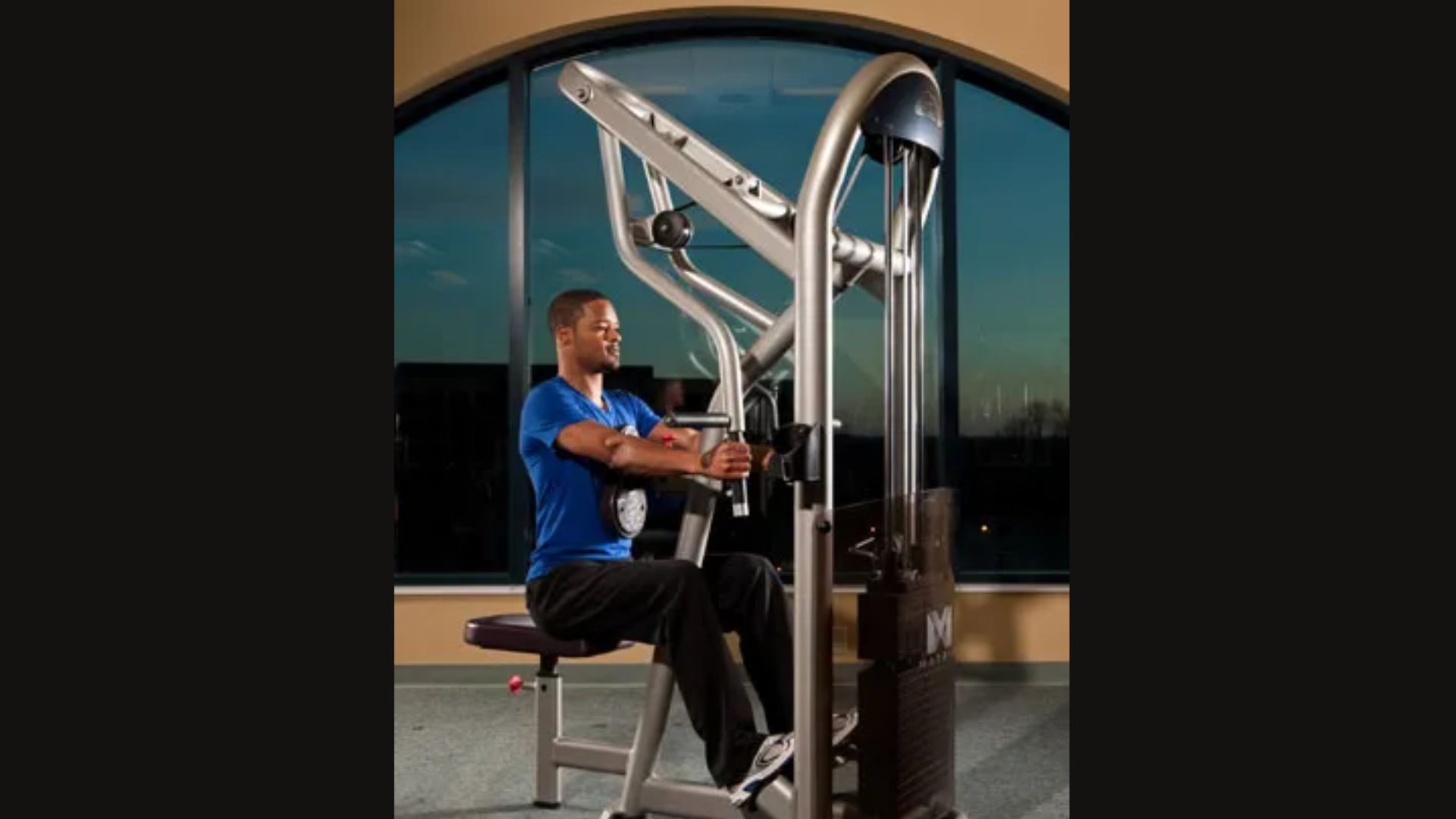 A man exercises on a gym machine, focusing on his workout in a well-equipped fitness center.