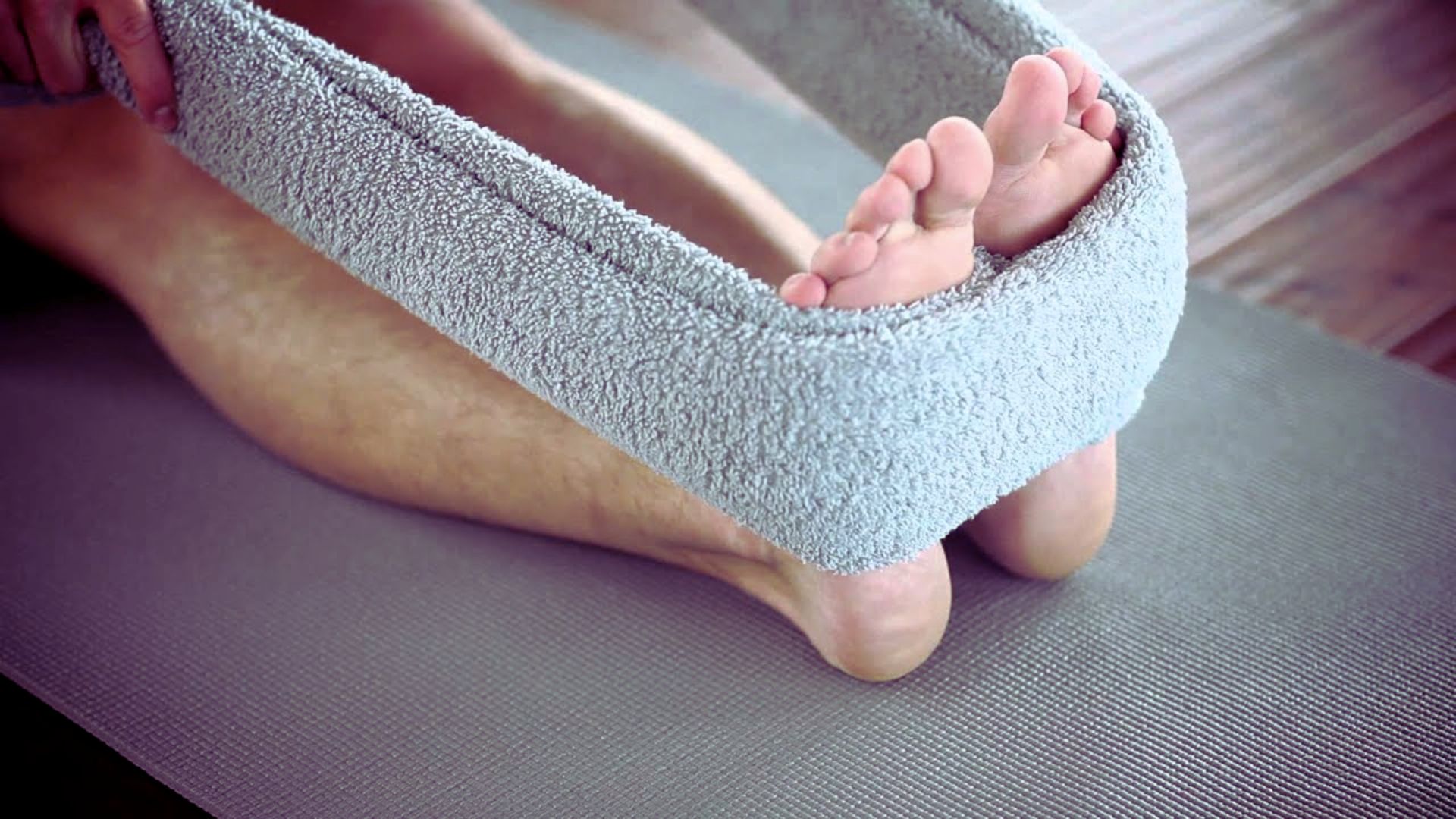 A person sits on a yoga mat with their feet elevated, practicing relaxation or meditation.