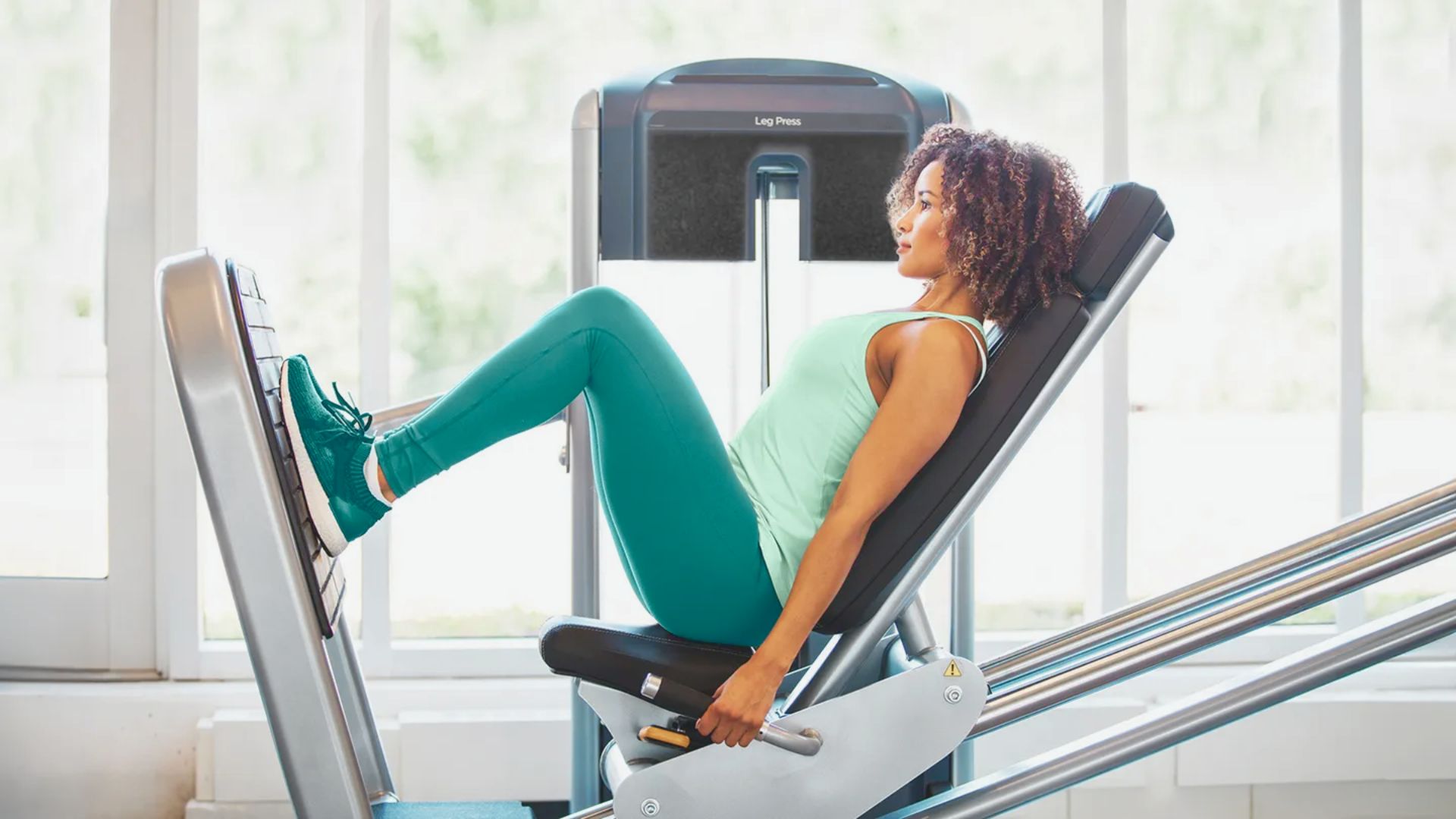 A woman sits on a gym machine, preparing for her workout in a fitness center.