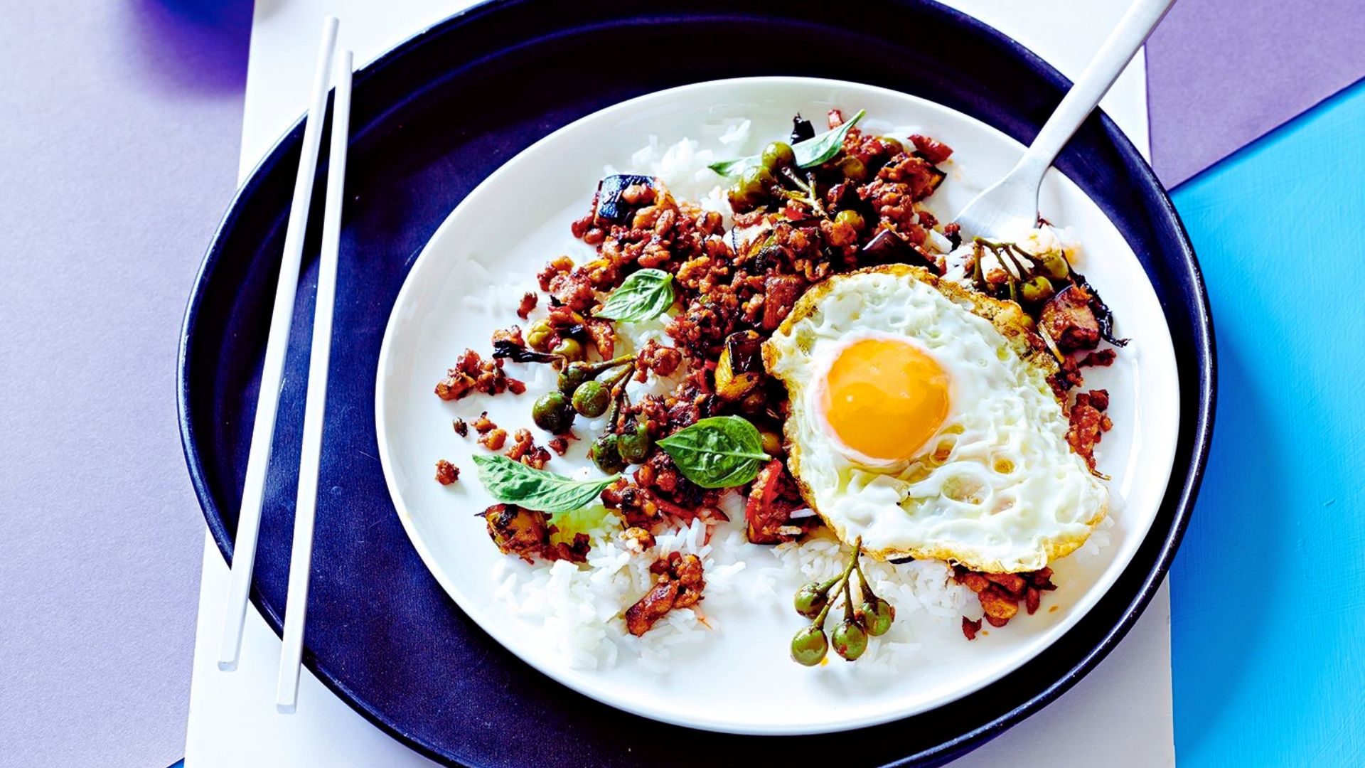 A serving of rice and vegetables topped with a perfectly fried egg on a white plate.