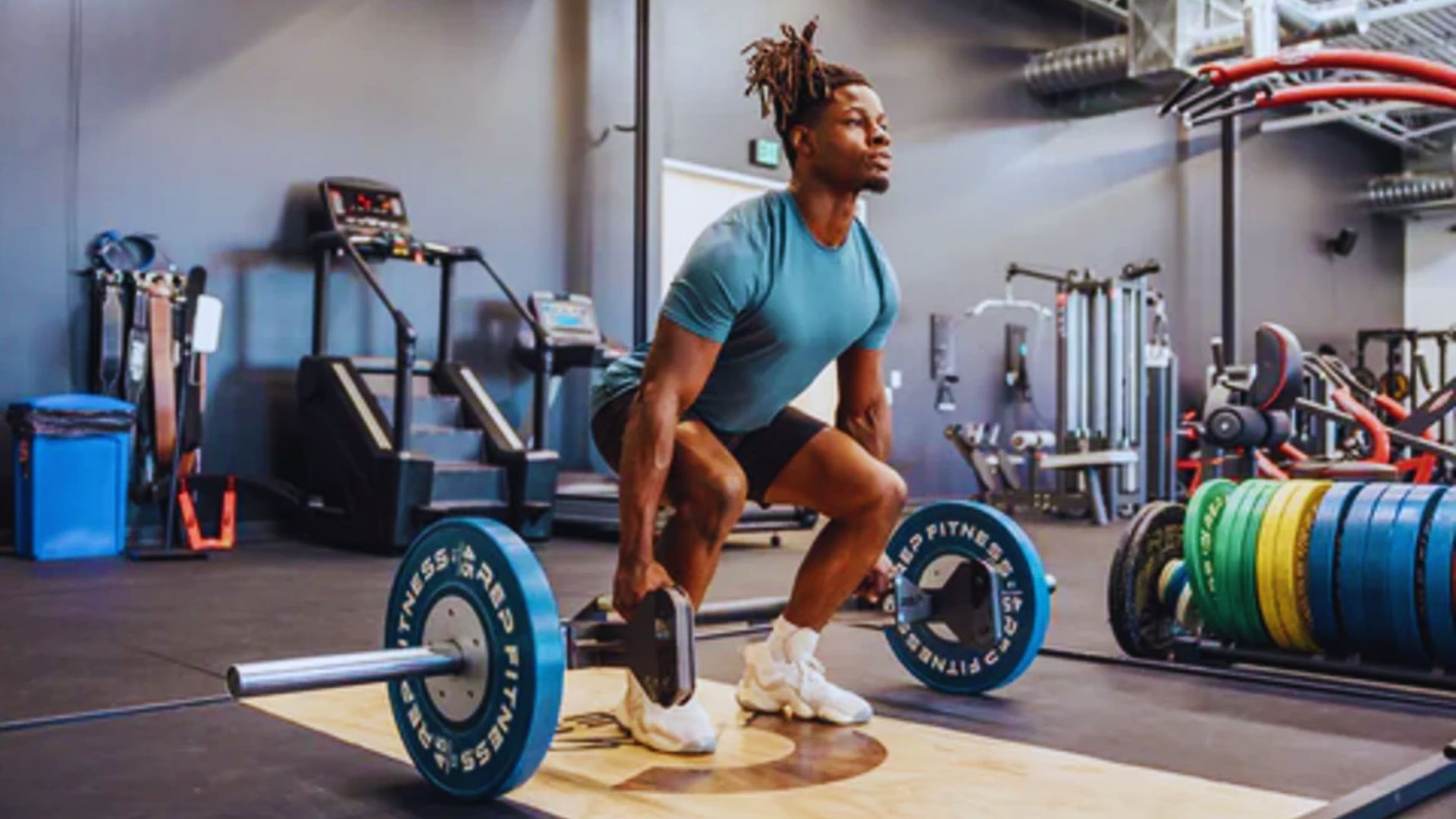 A man squats over a barbell in a gym, demonstrating proper form for Romanian deadlifts in a step-by-step guide.