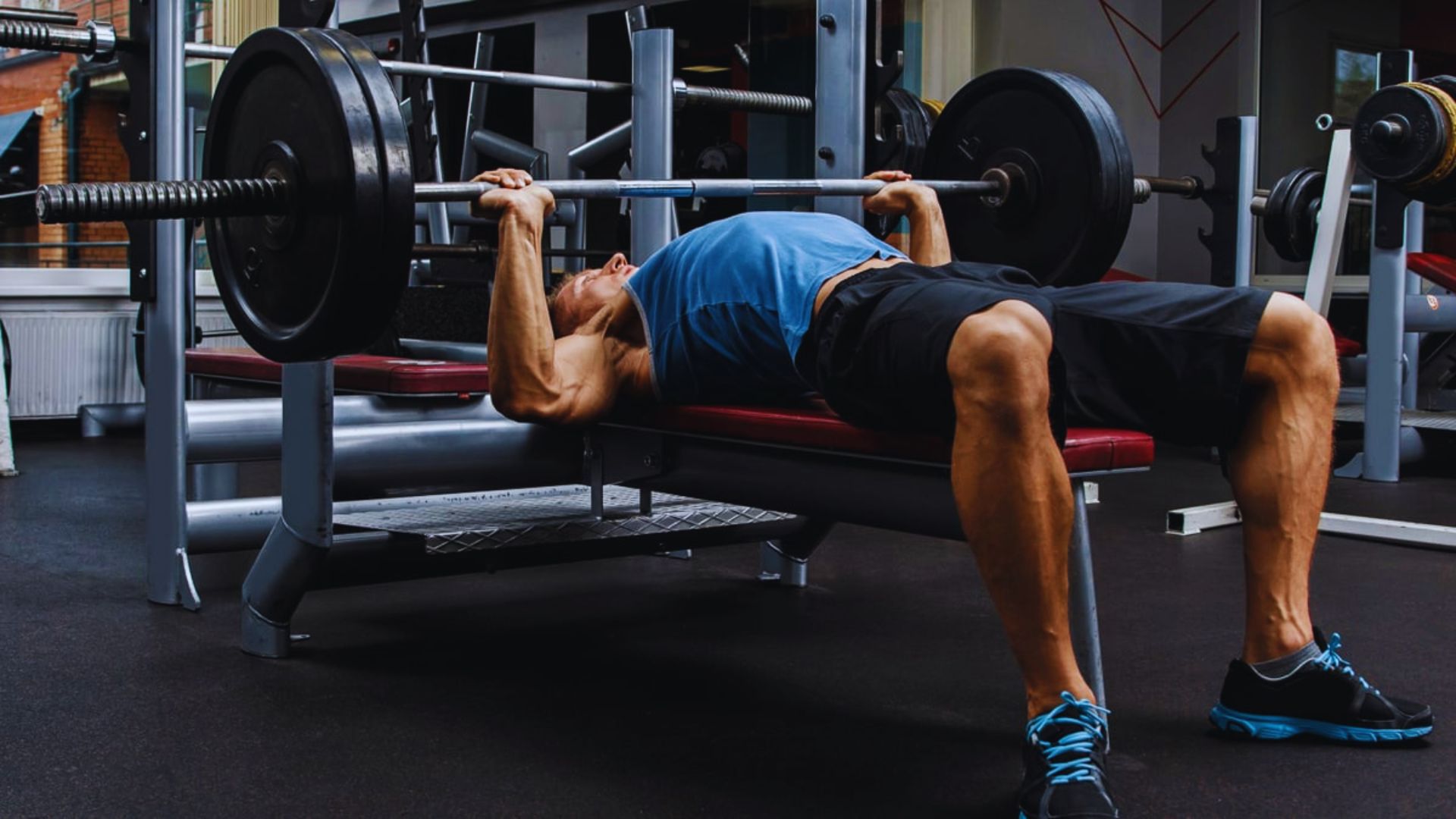 A man performing a bench press in a gym, focusing on strength training and fitness.