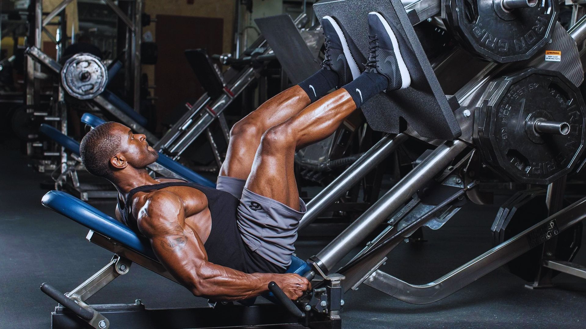 A man performs a leg press exercise in a gym, focusing on strengthening his quads, hamstrings, and calves.