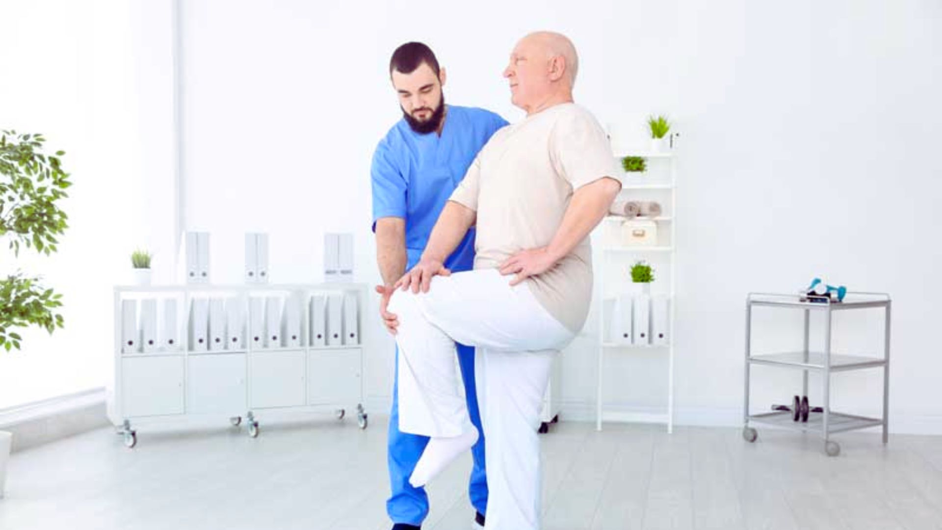 A man assists another man with a physical therapy exercise, focusing on rehabilitation and strength training.