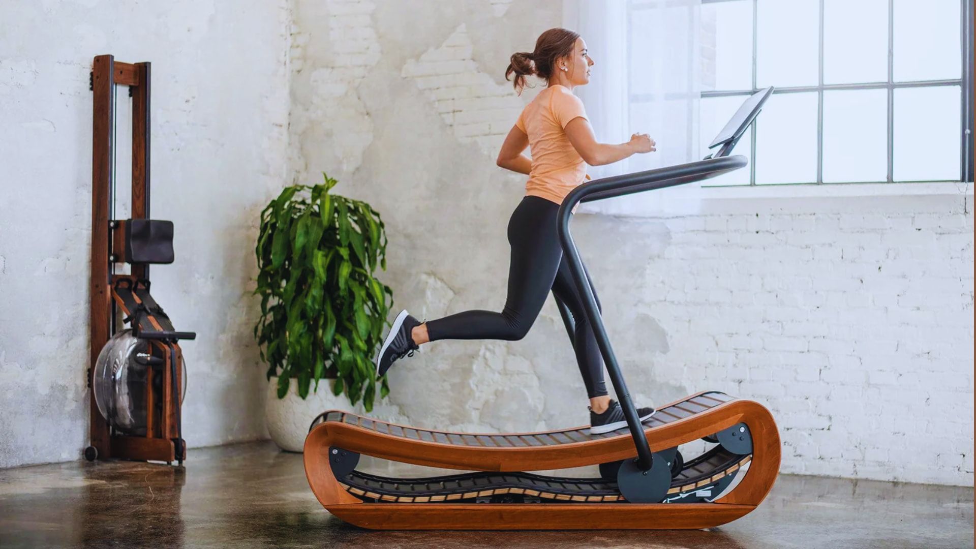 A woman runs on a treadmill in a well-lit room, focusing on her workout.